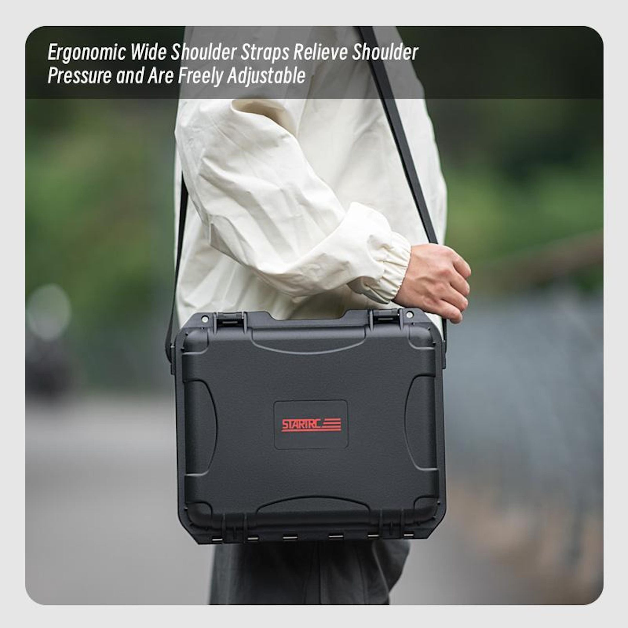 Person hält eine schwarze Tasche mit Schulterriemen. Die Tasche hat ein rotes STARIRC-Logo. Der Hintergrund ist verschwommen grün und grau.