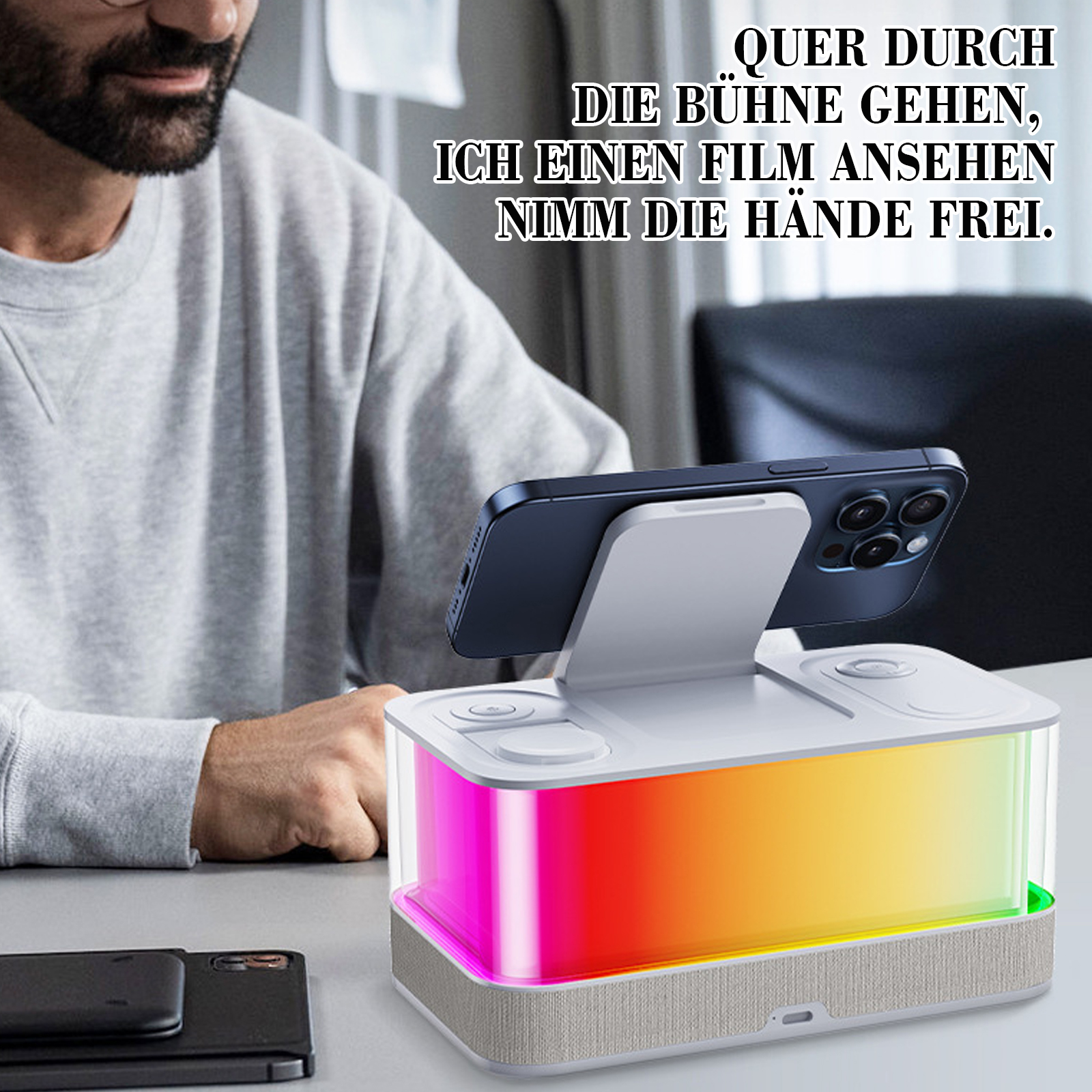 Ein Mann mit Brille und Bart neben einem Gerät, das ein Telefon hält. Das Gerät hat bunte Lichter.