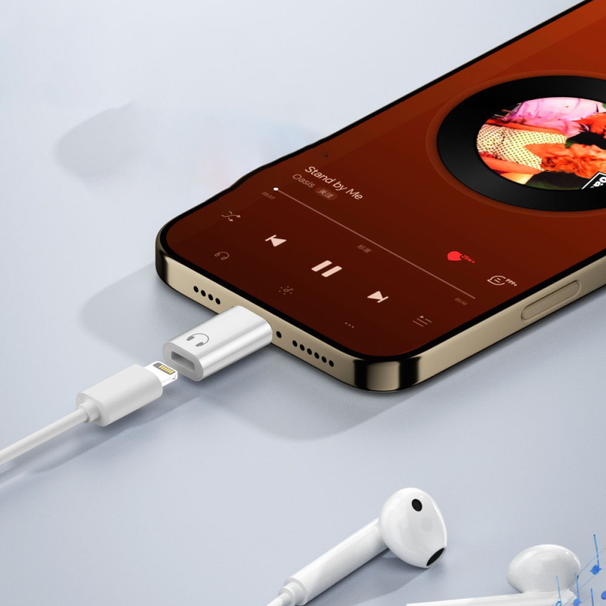 Ein Smartphone spielt Musik, verbunden über einen weißen Adapter mit weißen Ohrhörern. Adapter ist mit dem Telefon verbunden. Goldenes Telefon.