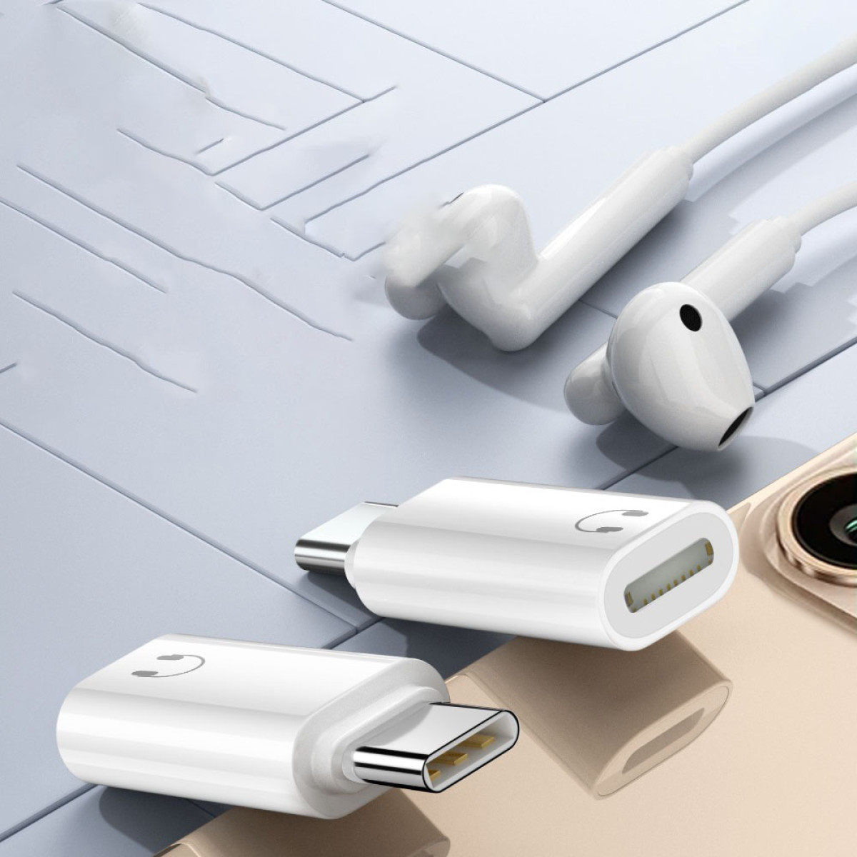 Weiße Kopfhörer, USB-C-Adapter und ein Smartphone auf hellblauem und goldenem Untergrund. Der Fokus liegt auf dem Zubehör.
