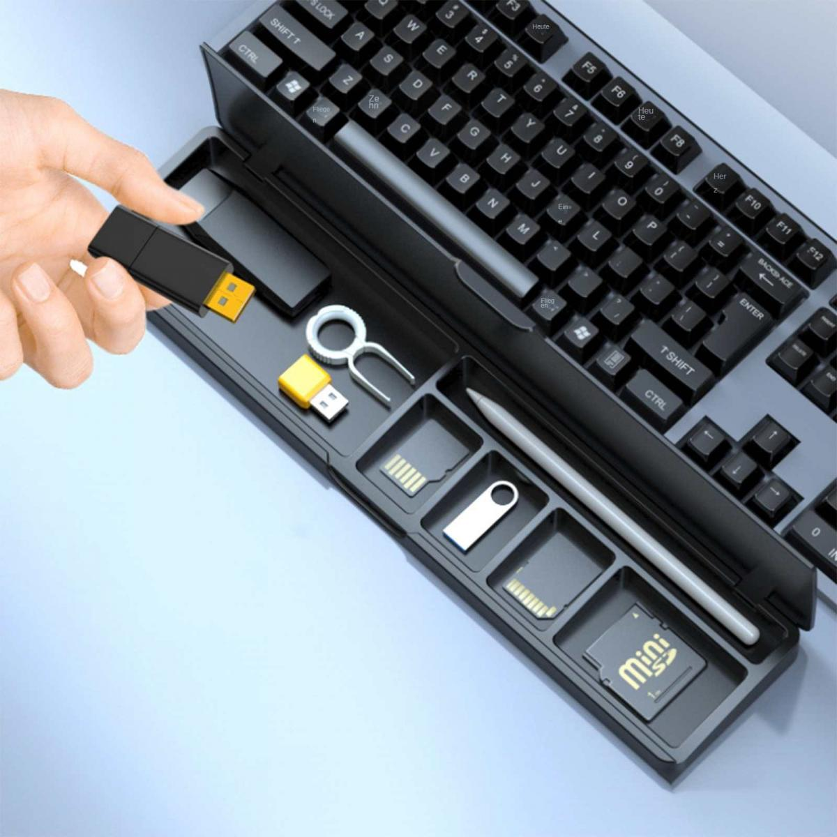 Hand hält einen USB-Stick über einem Schreibtisch-Organizer mit Tastatur und verschiedenen Tech-Zubehör. Schwarz-Gelb.