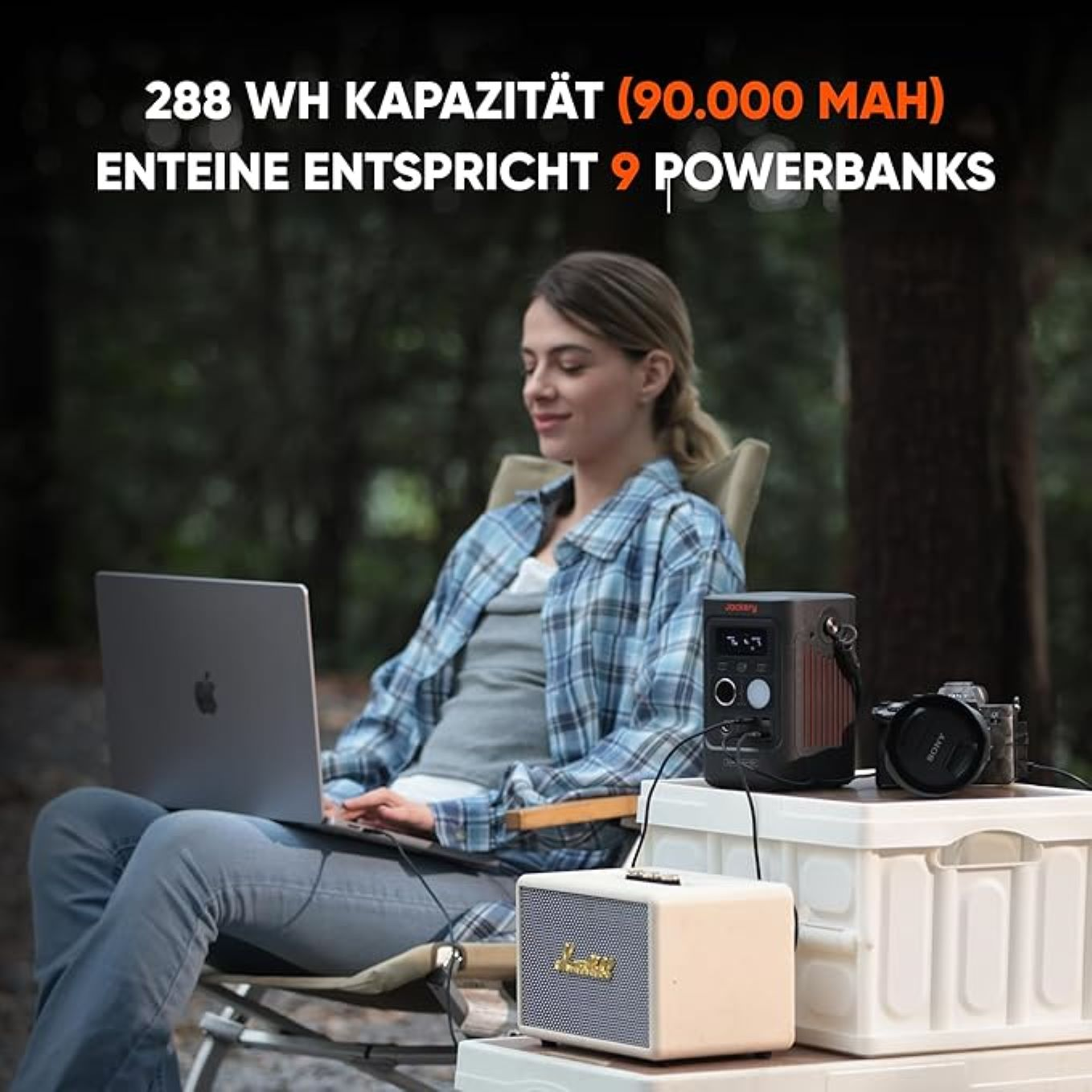 Frau sitzt draußen mit Laptop, Powerbank, Lautsprecher und Kamera. Waldhintergrund. Text oben: 288 Wh Kapazität.