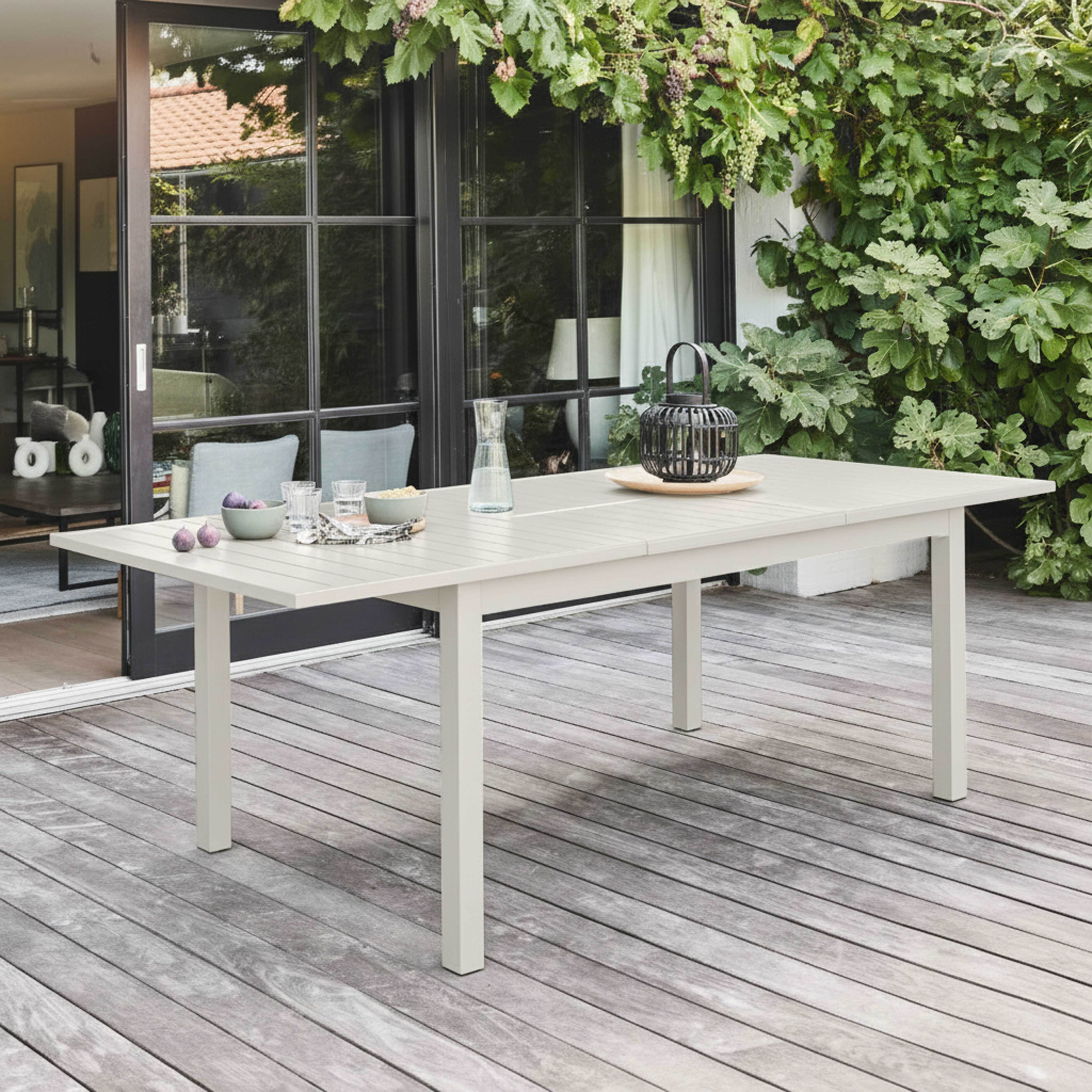 Esstisch im Freien, gedeckt. Mit Feigen, Gläsern und Wasserkrug. Auf einer Holzterrasse.