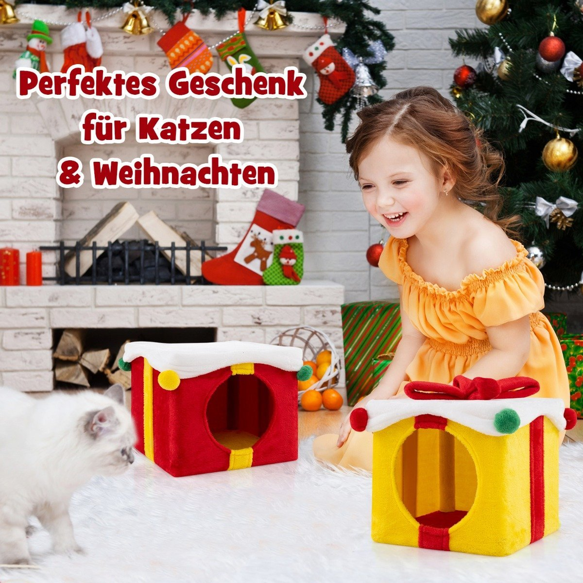 Una niña sonríe a casas para gatos. Un gato blanco está al lado de una roja. Una amarilla está frente a la niña. Decoraciones navideñas.