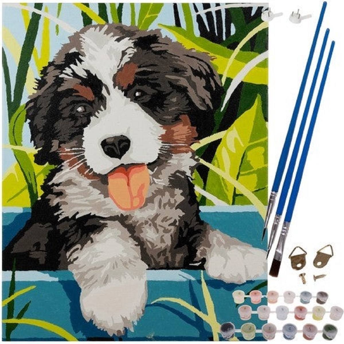 Un perro pintado con pelaje negro, blanco y marrón, con la lengua rosa afuera. Pinceles, pinturas y herrajes para colgar a la derecha.