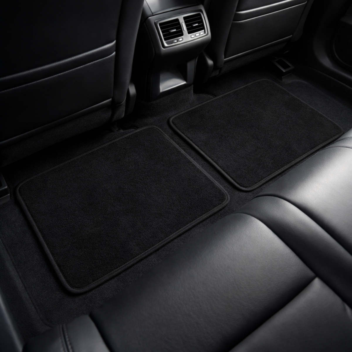 Auto-interieur. Zwarte vloermatten op tapijt. Leren stoelen op de voor- en achtergrond. Luchtgaten zichtbaar.
