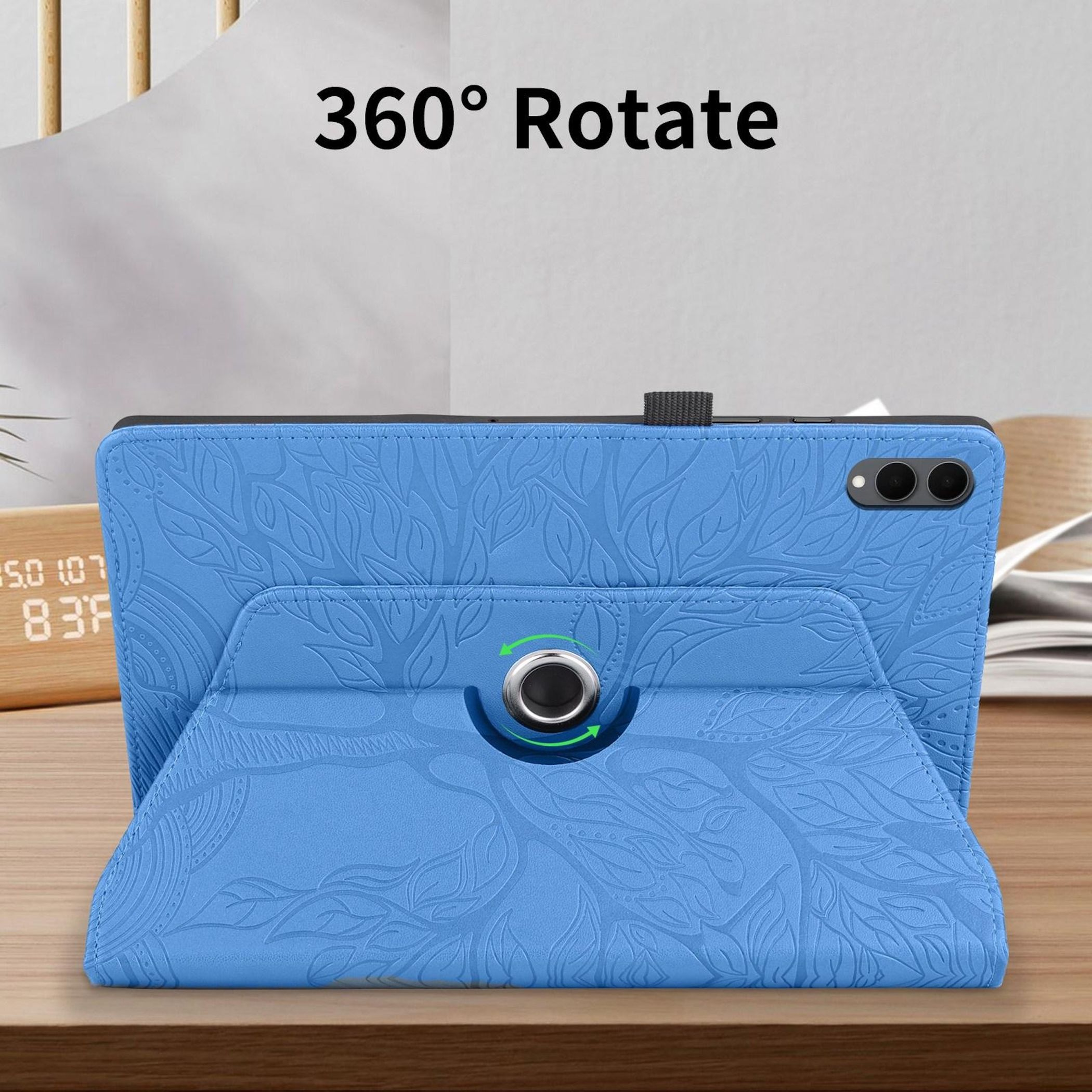 Una funda azul para tableta con un patrón floral se muestra sobre una mesa de madera, con un reloj digital en el fondo.
