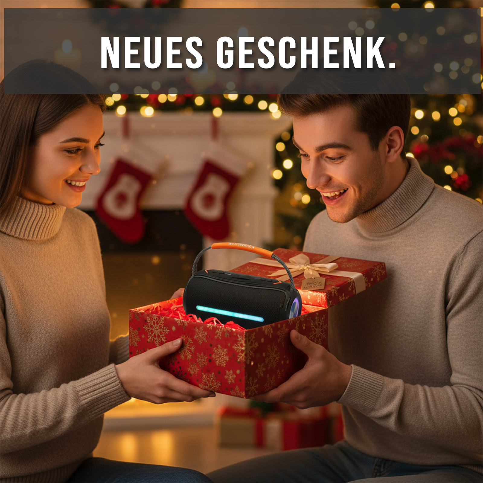 Ein Paar öffnet eine Geschenkbox mit einem Lautsprecher. Der Hintergrund zeigt einen Weihnachtsbaum und Strümpfe.