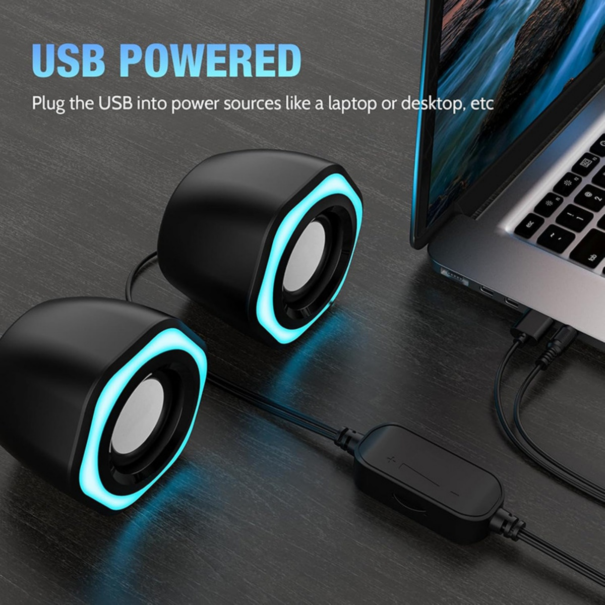 Zwei schwarze USB-Lautsprecher mit blauem Licht, verbunden mit einem Laptop. Lautstärkeregler sichtbar. Text: 'USB POWERED'.