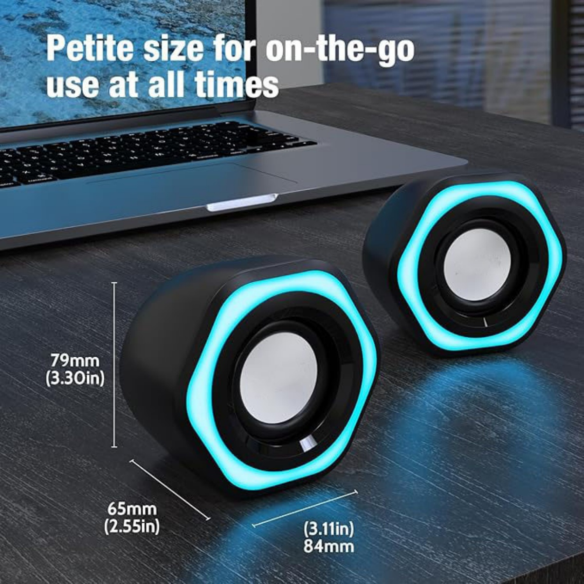 Zwei schwarze Lautsprecher mit blauen Lichtakzenten stehen auf einer Holzoberfläche in der Nähe eines Laptops. Abmessungen sind angegeben.