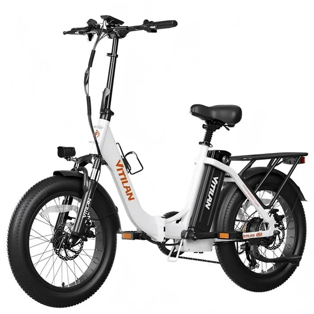 Una bicicleta eléctrica VITILAN blanca y negra. Tiene neumáticos anchos, un asiento negro y una parrilla trasera. El logotipo de la marca es visible.