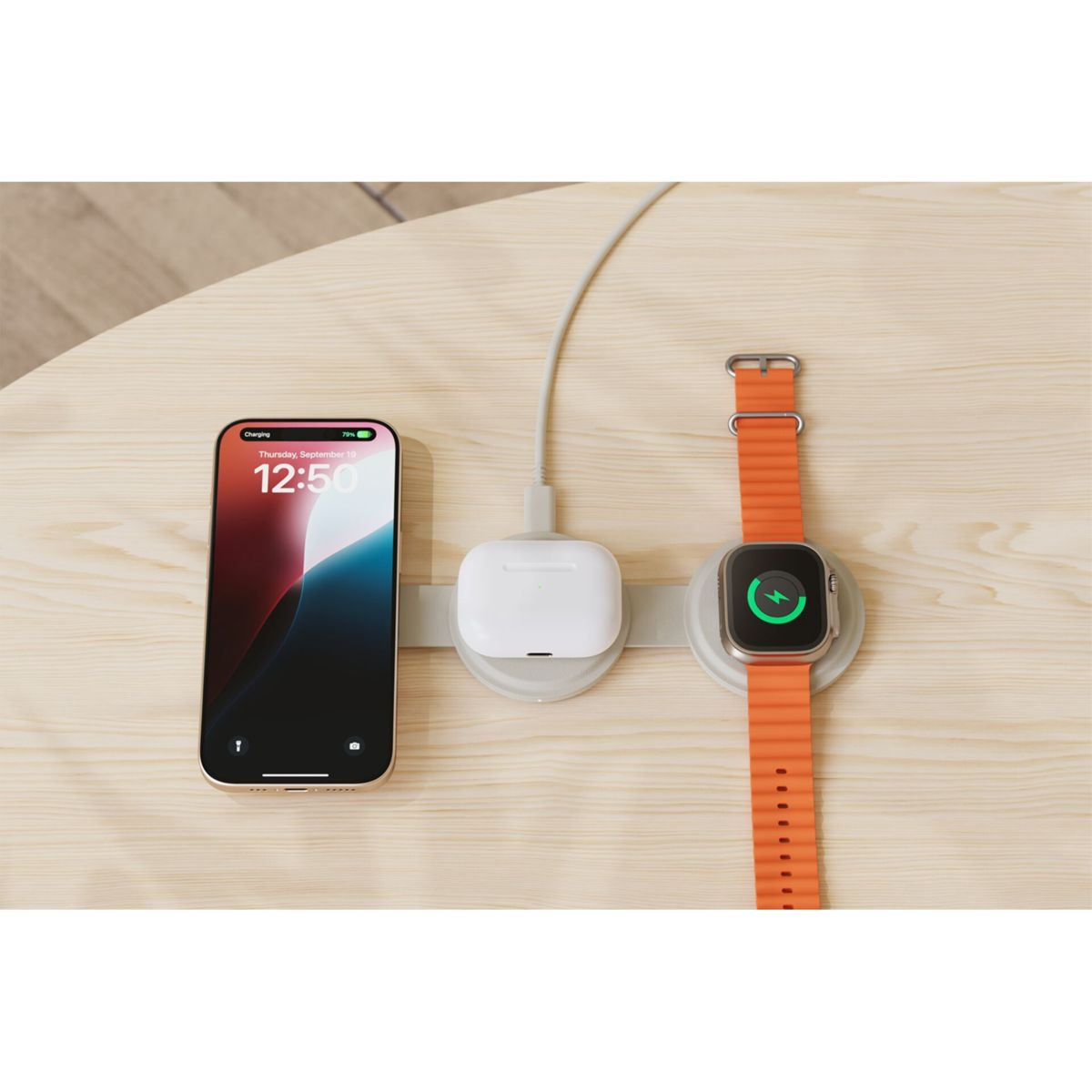 Ein Telefon, AirPods und eine Apple Watch laden auf einem Holztisch. Das Telefon zeigt die Uhrzeit an. Die Uhr hat ein orangefarbenes Armband.