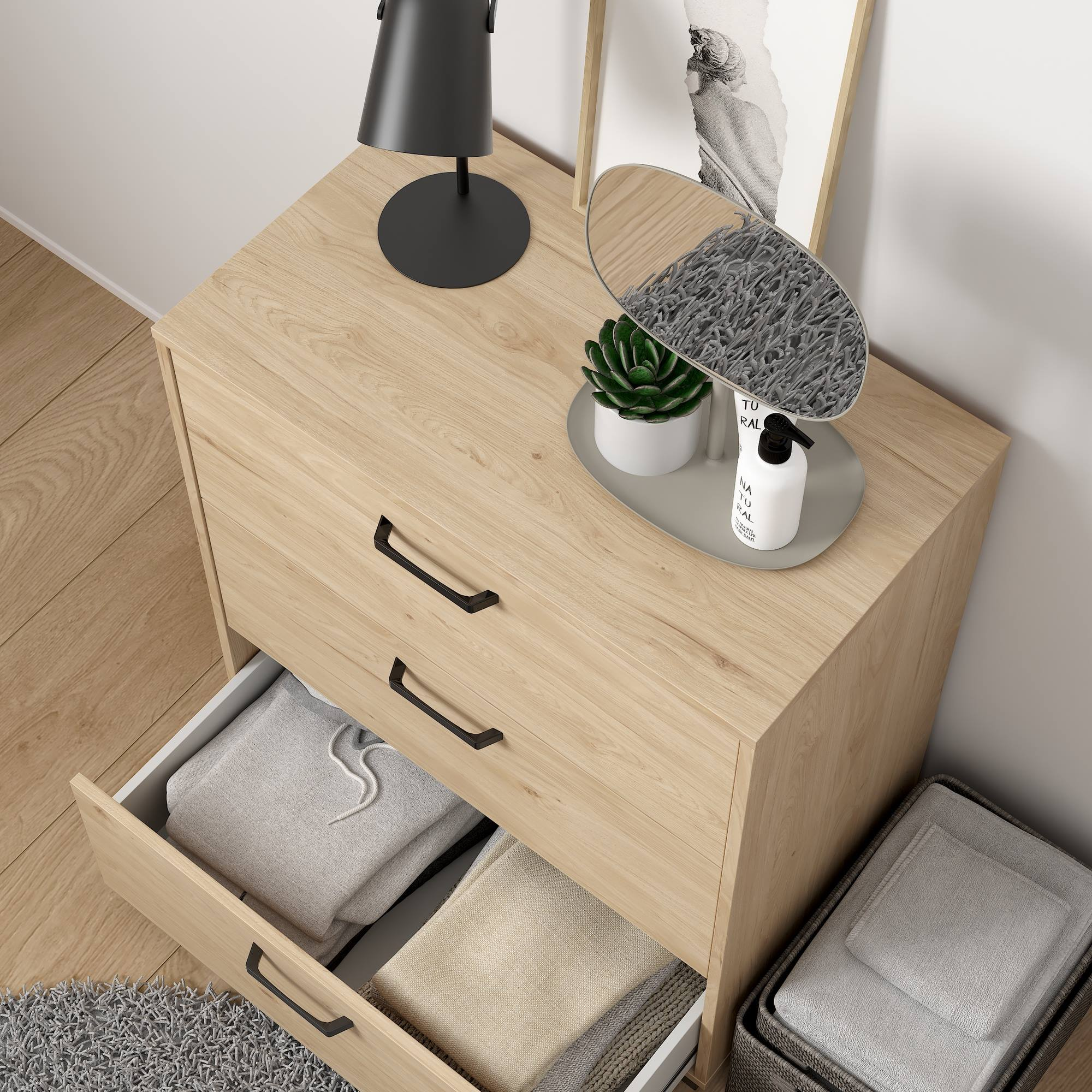 Mesita de noche de madera con cajón abierto. Encima: espejo, planta, lámpara. Otro cajón abierto con ropa.