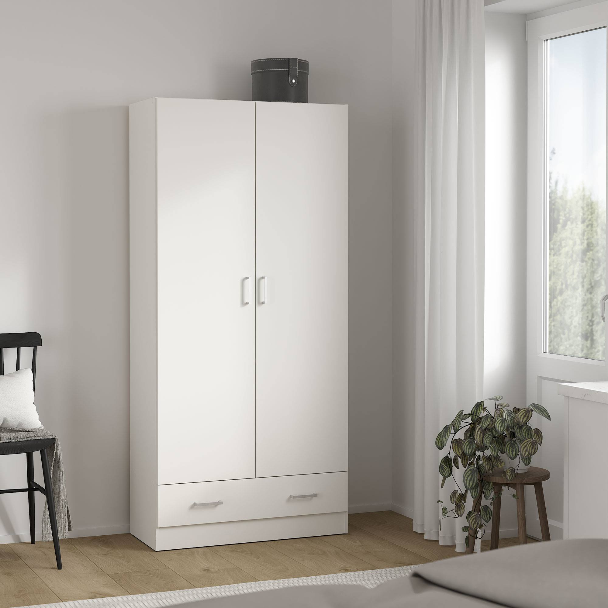 Un armario blanco con dos puertas y un cajón, una silla negra, una planta en un taburete de madera y una ventana con cortinas blancas.