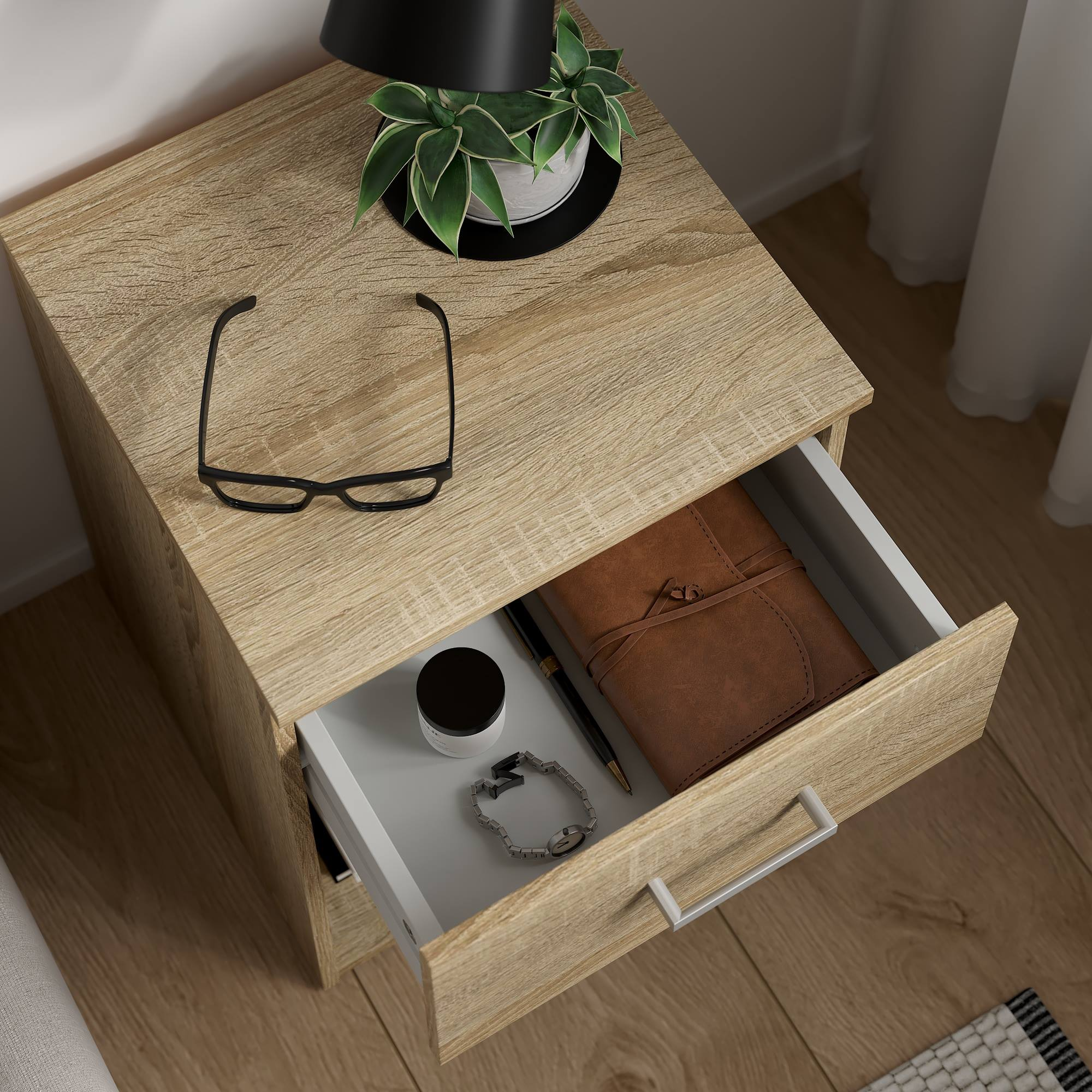 Mesita de noche de madera con cajón abierto. Dentro: diario, reloj, bolígrafo, frasco pequeño. Encima: gafas, planta.