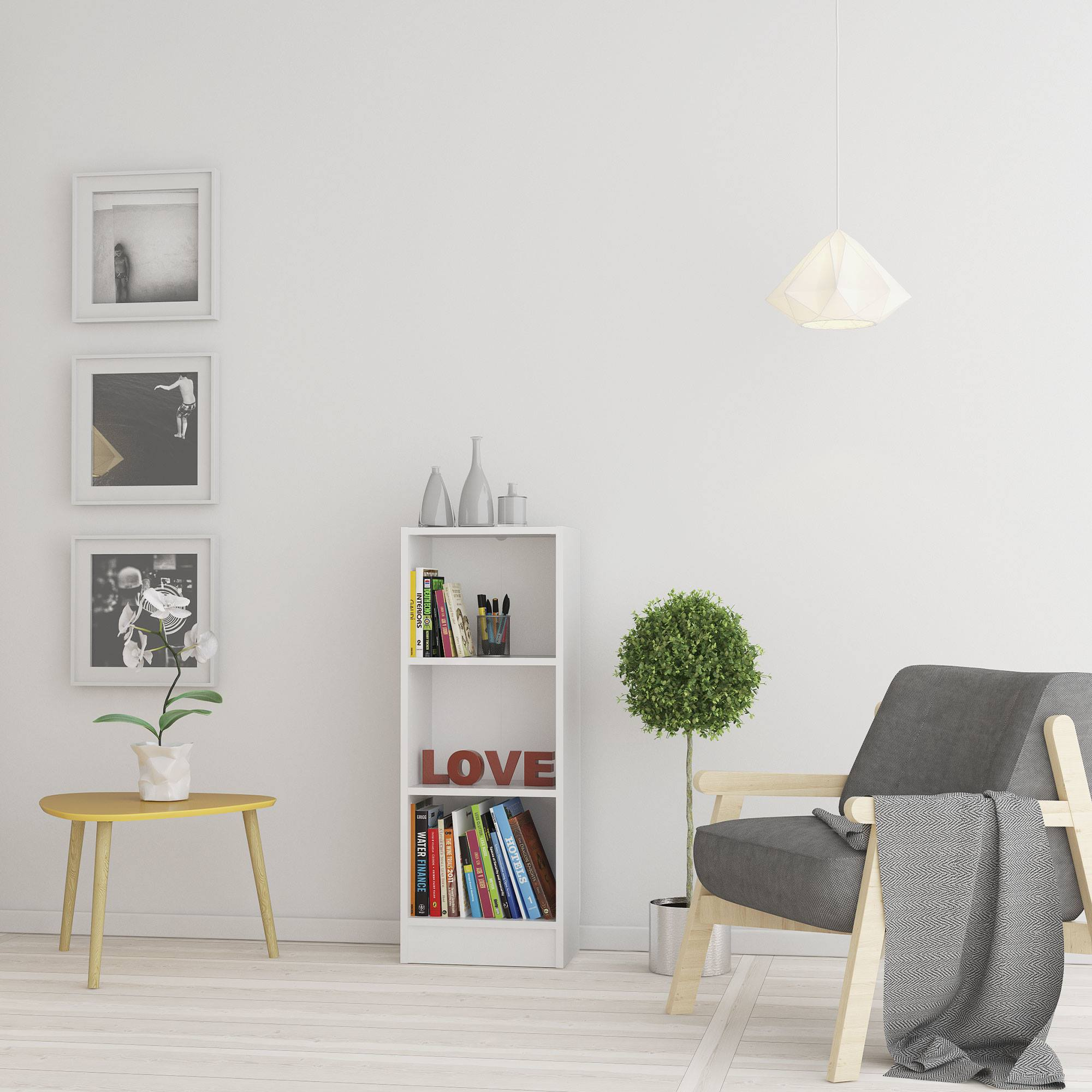 Una habitación con paredes blancas, un sillón gris, un árbol pequeño, una estantería y fotos enmarcadas.