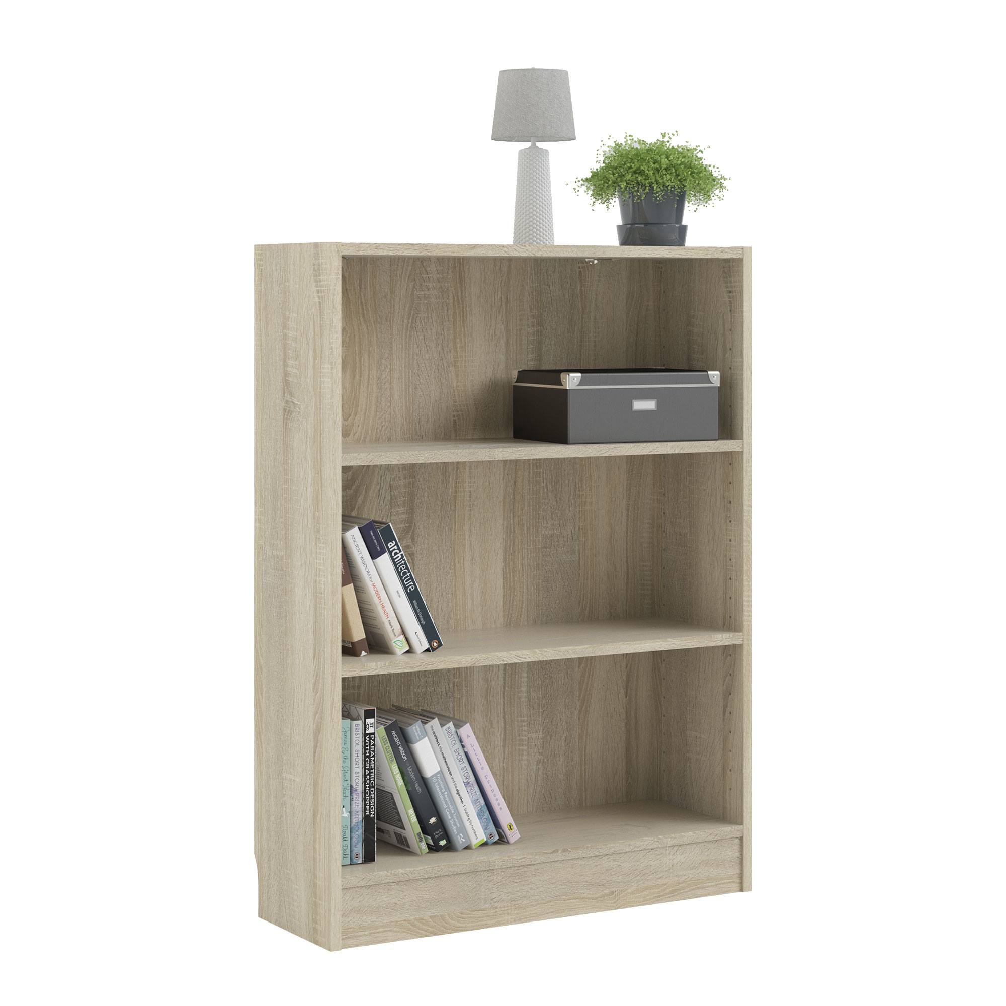 Una estantería de madera clara con libros, una lámpara, una planta y una caja gris en sus estantes.