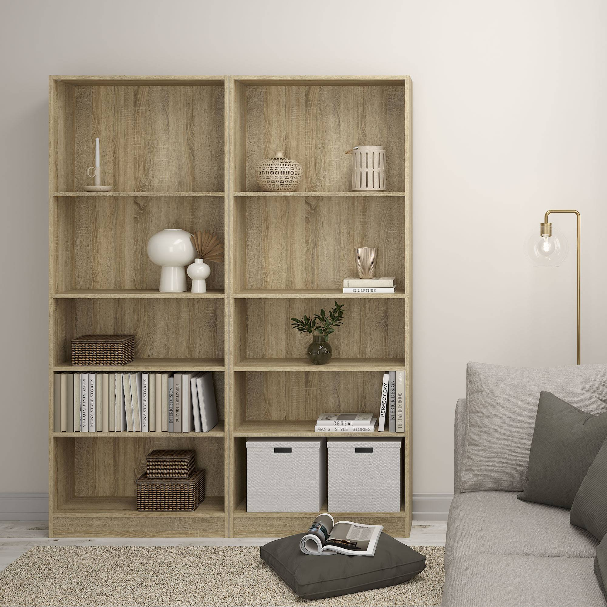 Una habitación con estanterías de madera, libros, elementos decorativos, un sofá y una lámpara de pie. También hay una alfombra y una revista.