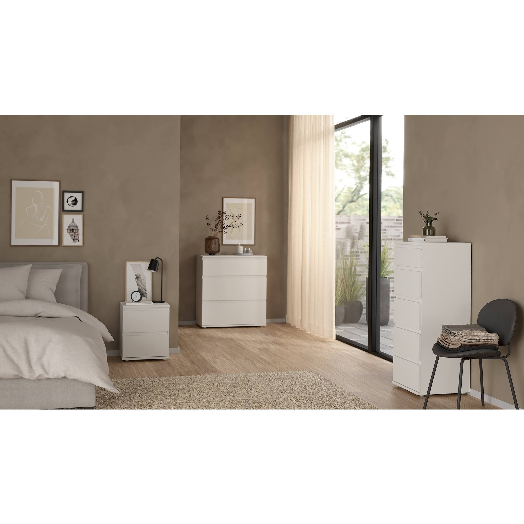 Escena de dormitorio con cama, cómodas, arte y silla. Dominan los tonos neutros. Ventana con vista exterior.
