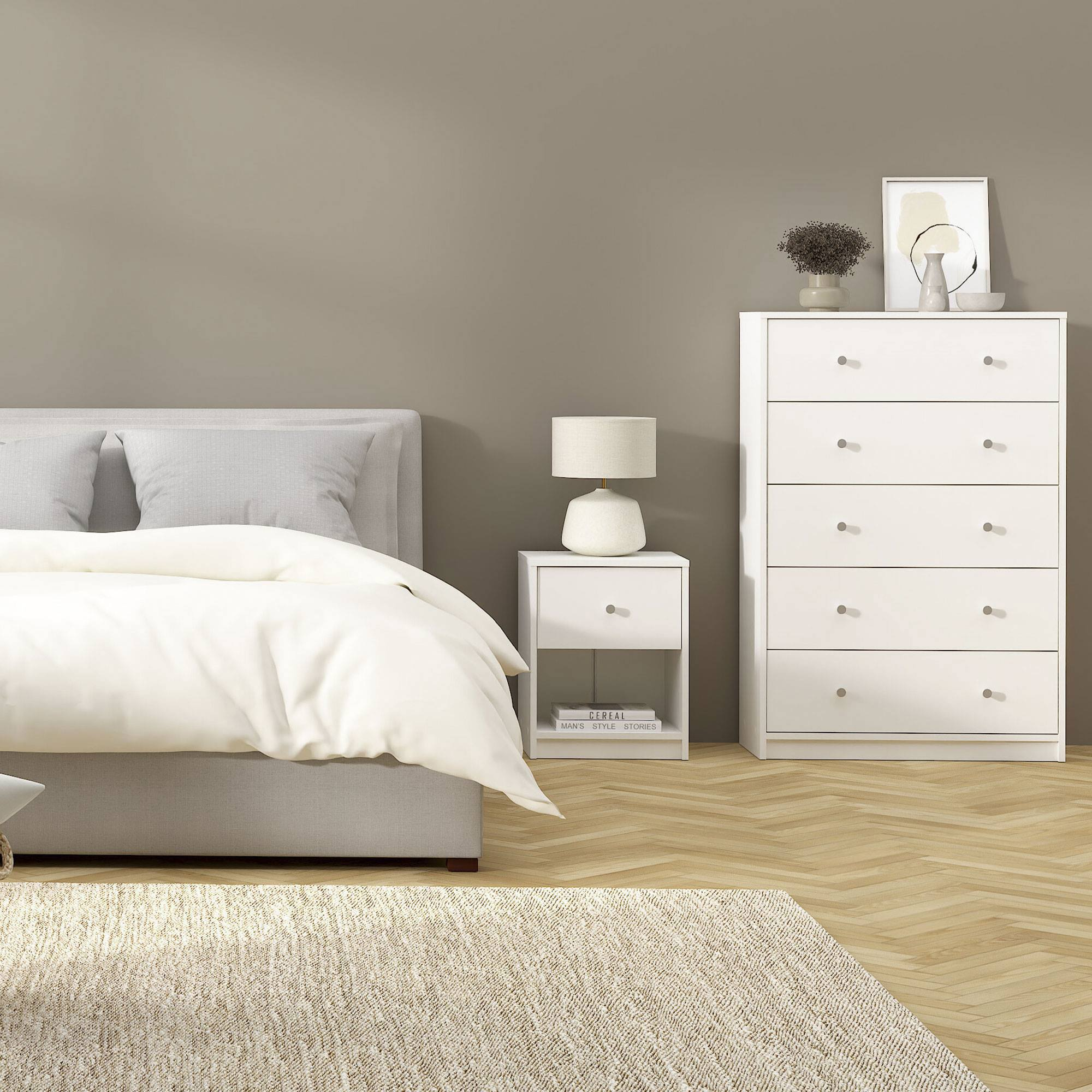 Escena de dormitorio con cama, cómoda blanca, mesita de noche, lámpara, alfombra y suelo de madera en espiga.