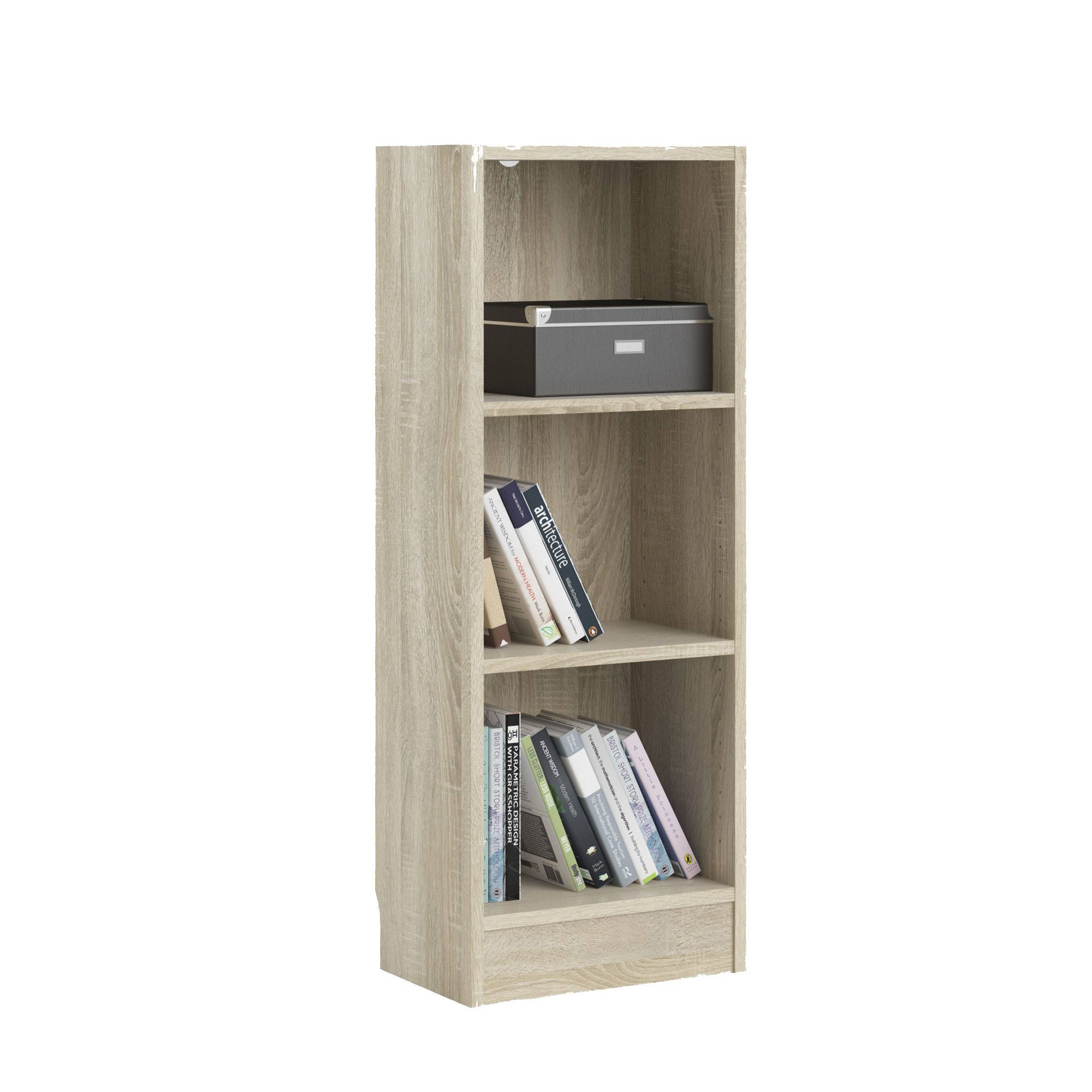 Una estantería de madera clara con libros y una caja gris. Los libros tienen títulos como 'Arquitectura' y 'Bristol Short Story Prize'.