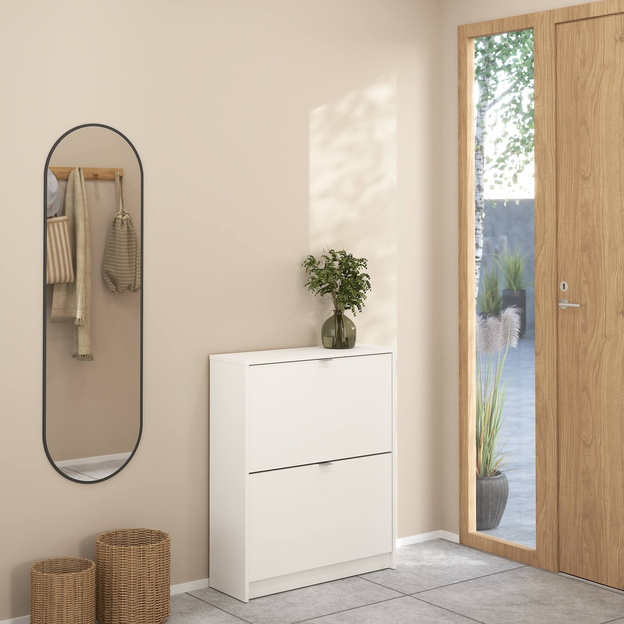Pasillo con espejo, mueble zapatero blanco y puerta de madera exterior. Hay dos cestos de mimbre.