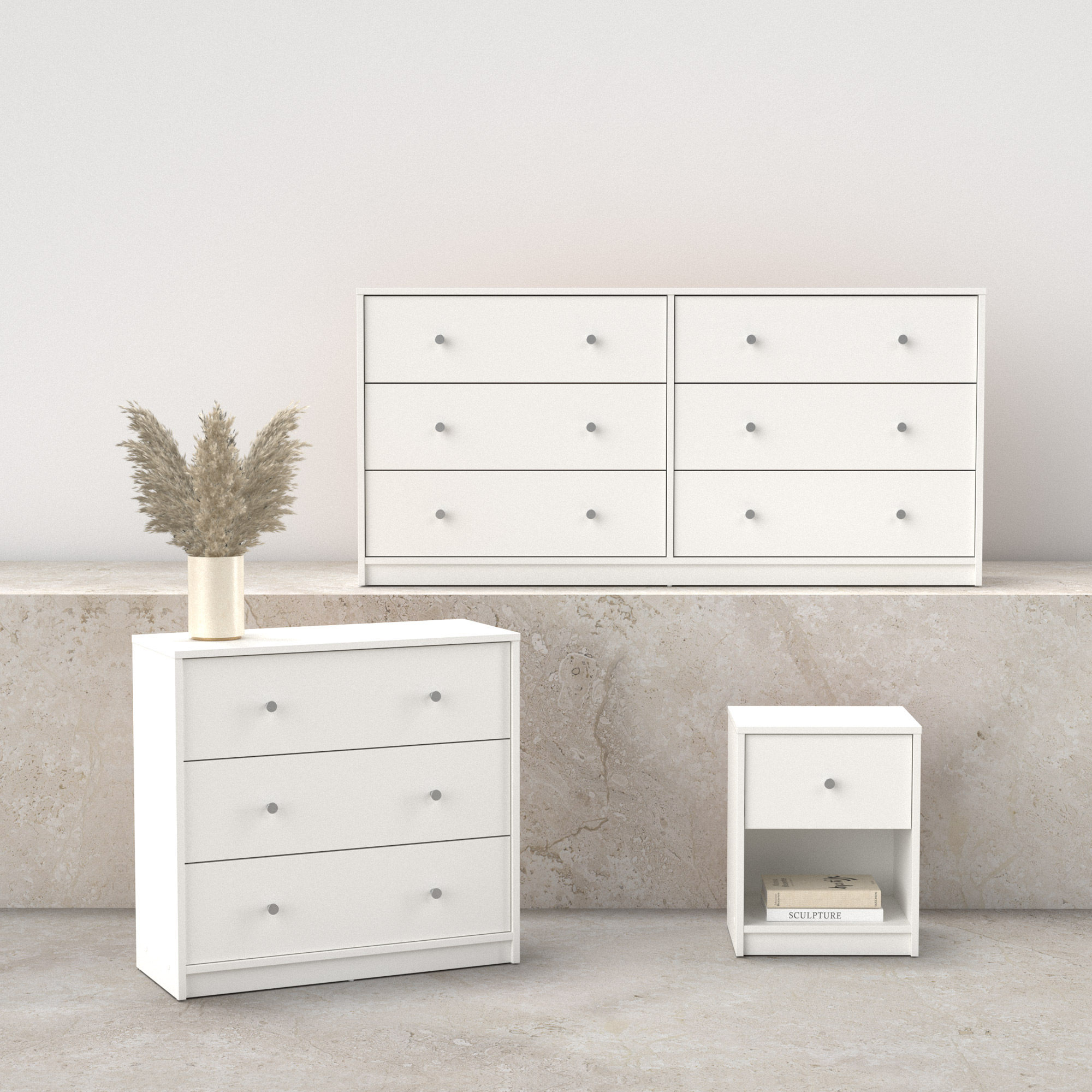 Tres cómodas blancas y una mesita de noche. Un jarrón con flores secas encima de una cómoda. Fondo beige.
