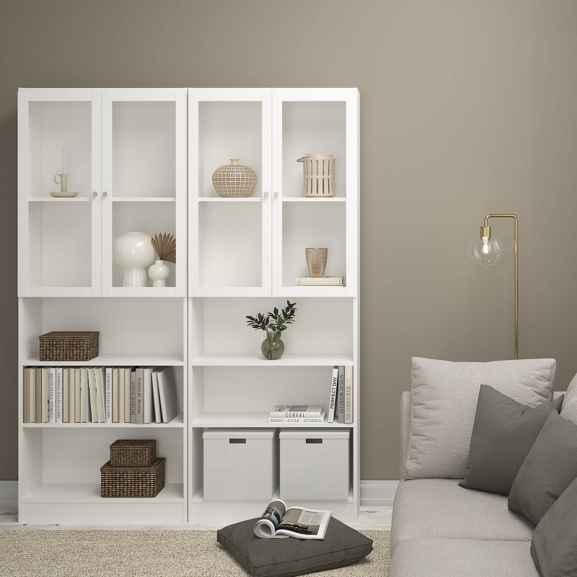 Una estantería blanca con puertas de cristal, que contiene decoración y libros. Un sofá y una lámpara de pie están en el lado derecho de la imagen.