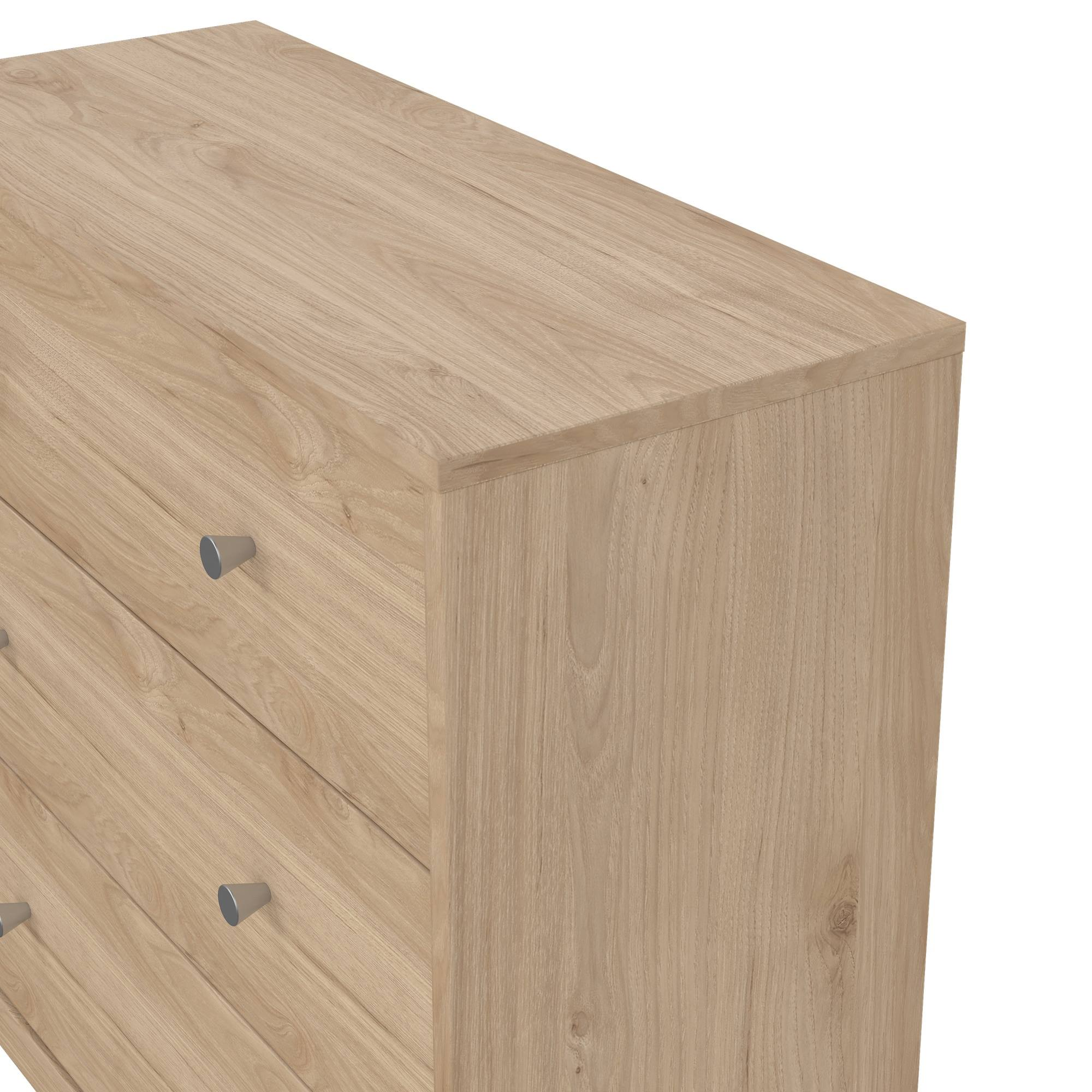 Una cómoda de madera clara con tres cajones y tiradores plateados. También se ve el lateral de la cómoda.