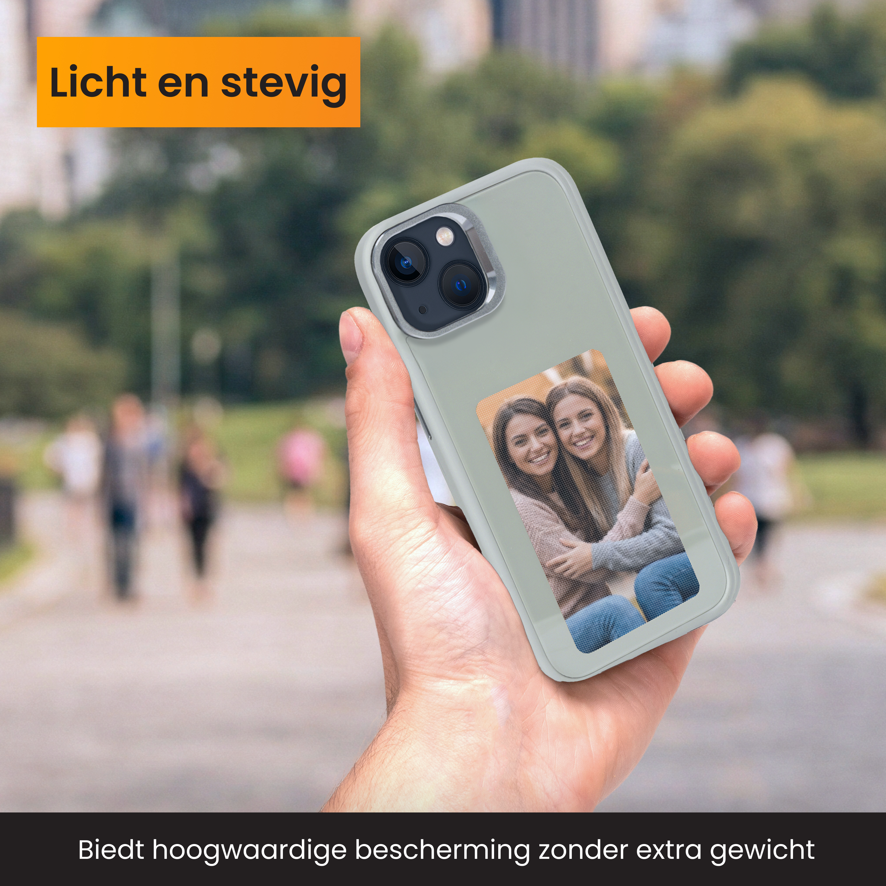 Eine Hand hält ein Telefon mit einem Bild von zwei Frauen. Der Hintergrund ist eine verschwommene Parkszene.