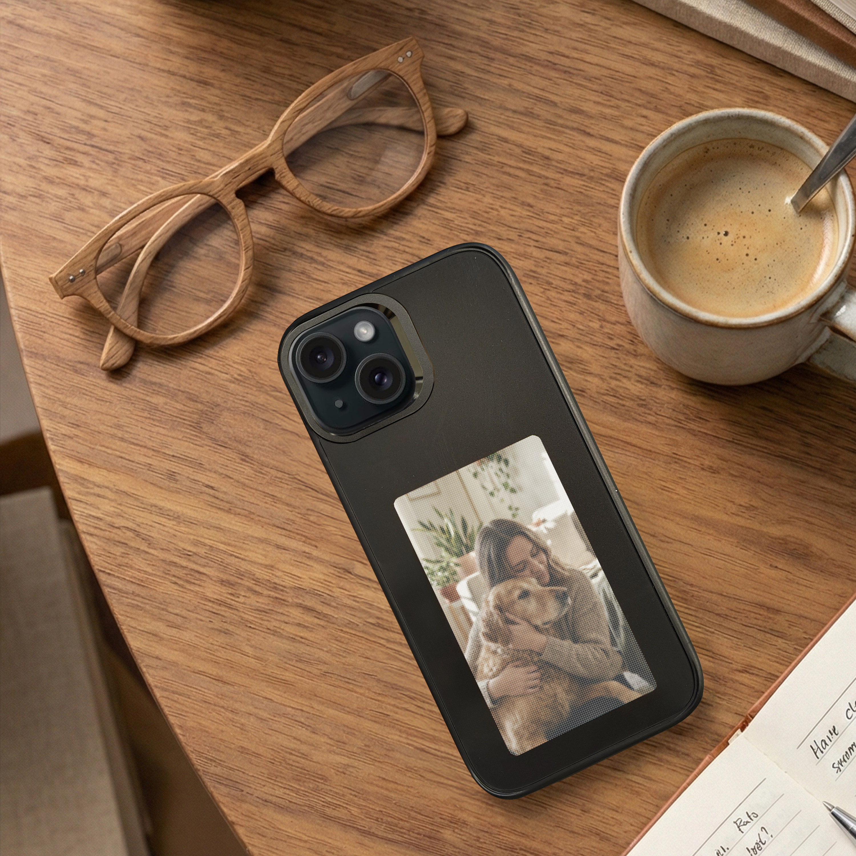 Ein Telefon mit einem Hundefoto auf einem Holztisch, mit Brille und Kaffeetasse.