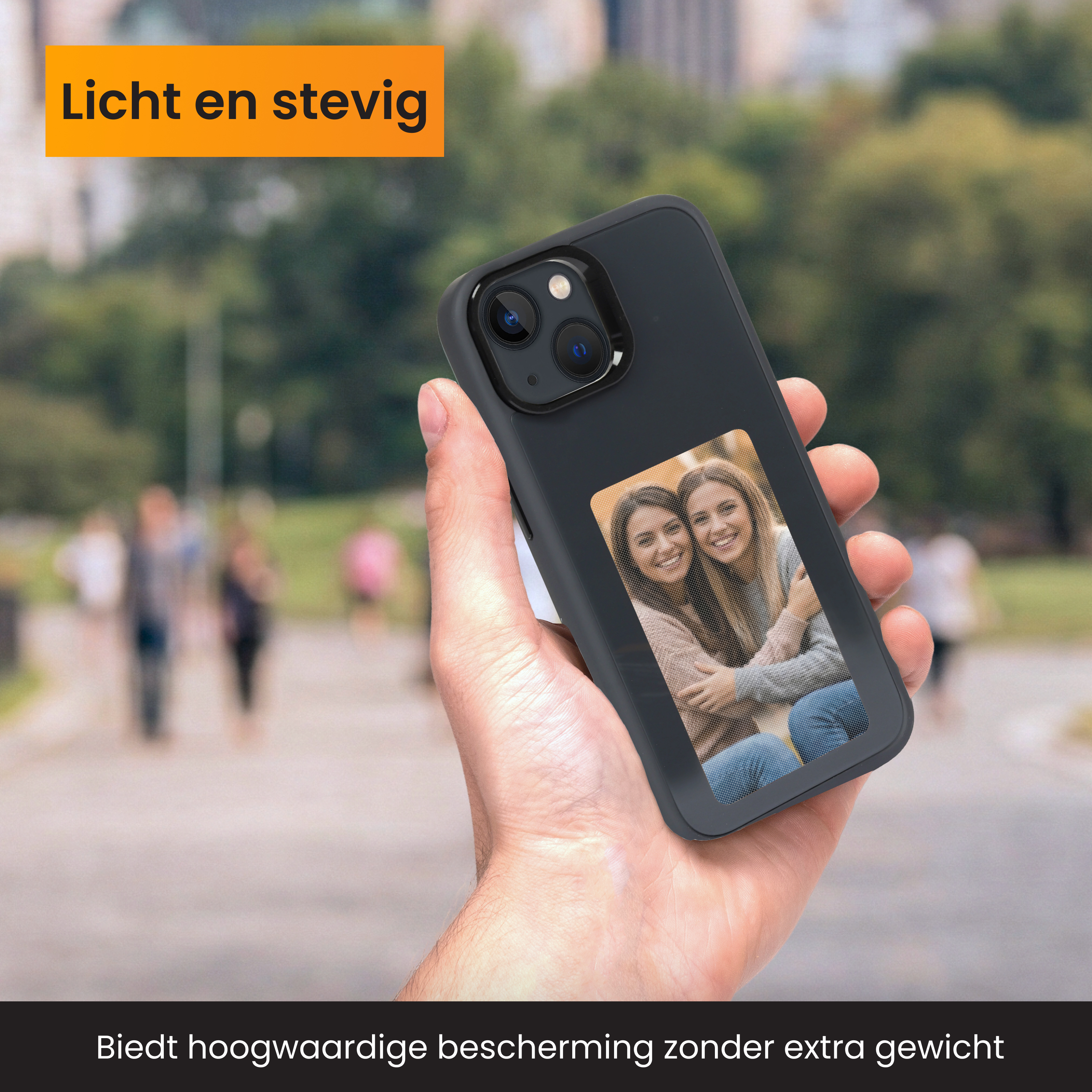 Eine Hand hält ein Telefon mit Hülle. Das Telefon zeigt ein Foto von zwei Frauen. Der Hintergrund ist ein verschwommener Park.