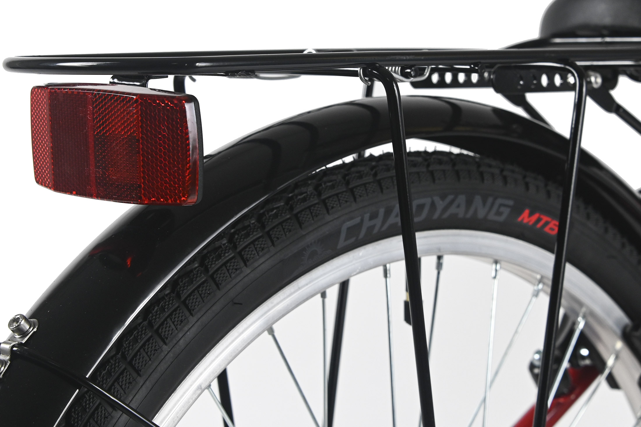 Nahaufnahme eines Fahrrad-Hinterrads. Ein roter Reflektor ist an der schwarzen Gepäckträger befestigt. Der Reifen sagt 'CHAYANG MTB'.