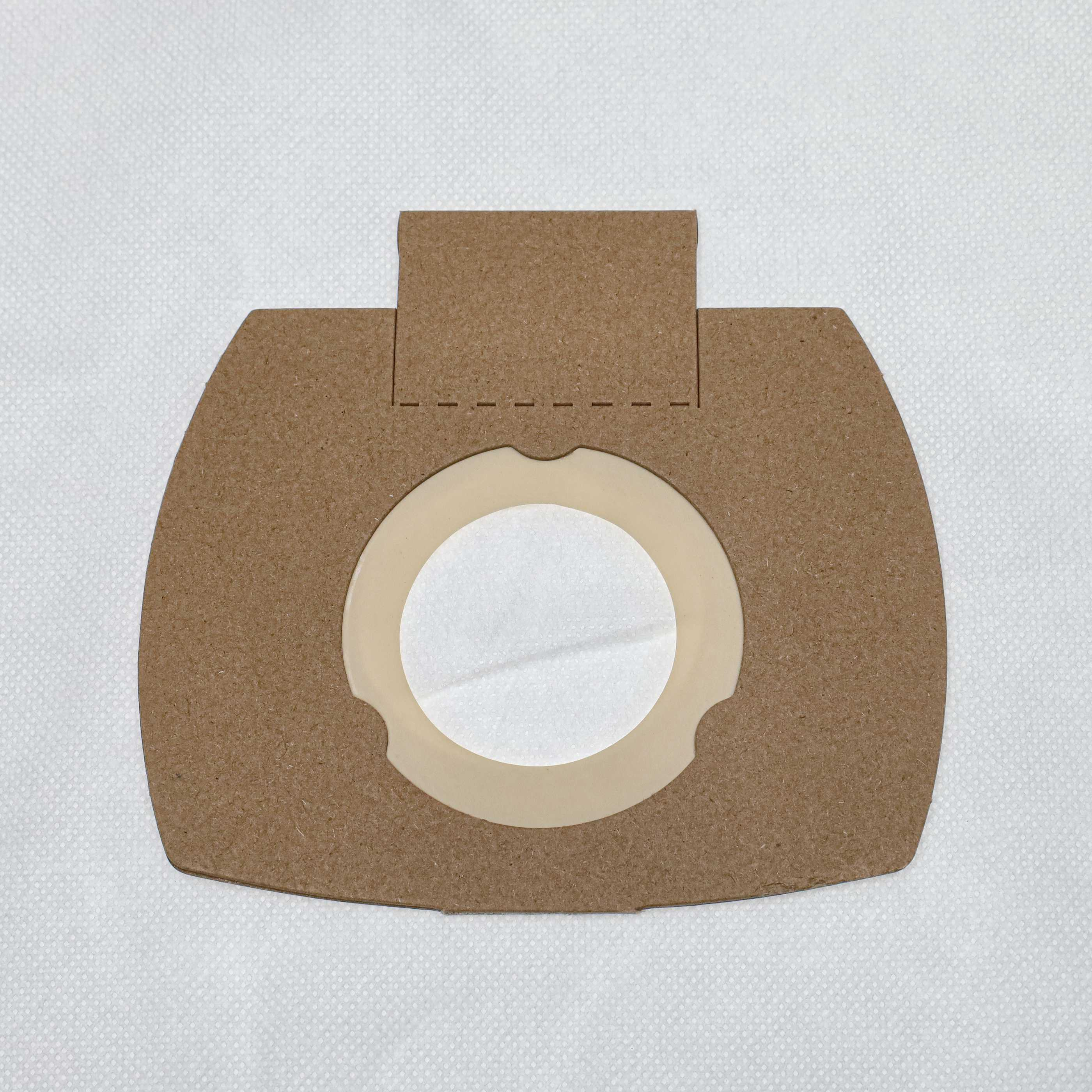 Ein brauner Papier-Staubsaugerfilter auf weißem strukturierten Hintergrund. Der Filter hat eine kreisförmige Öffnung.