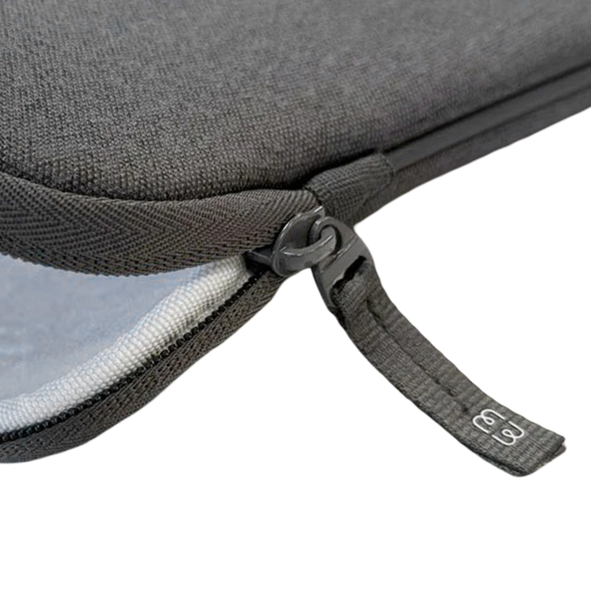 Primo piano di una custodia grigia per laptop con cerniera. La cerniera è parzialmente aperta, rivelando l'interno bianco.