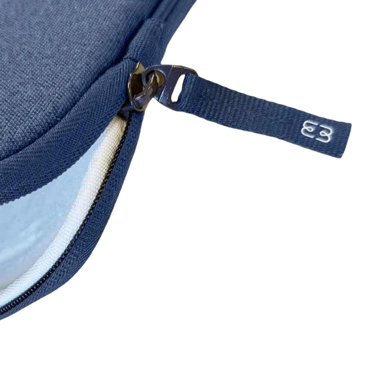 Primo piano di una custodia per laptop blu navy con cerniera. Il tirazip ha il logo 'E3'. Interno bianco visibile.