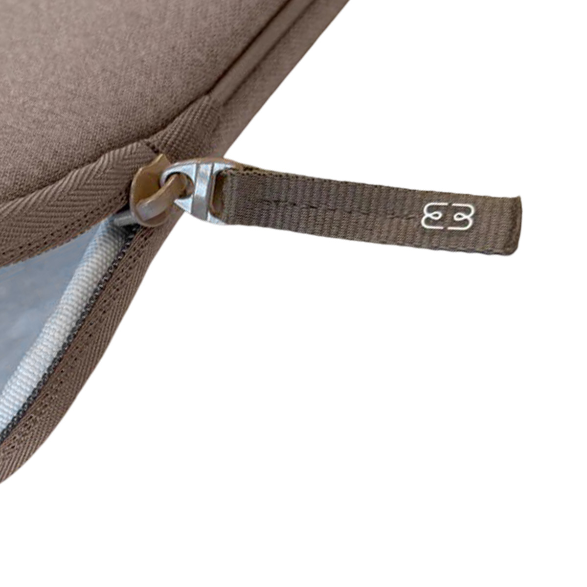 Primo piano di una borsa marrone con cerniera. La cerniera ha le lettere 'E3'. Lo sfondo è bianco.