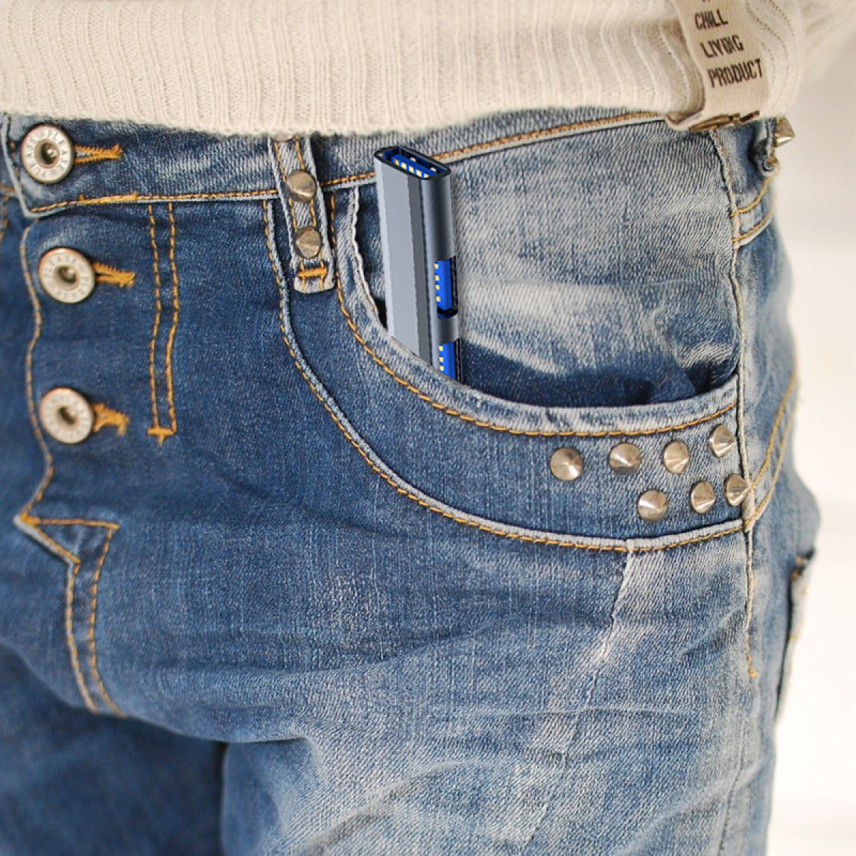 Szara i niebieska zapalniczka jest w kieszeni dżinsów. Kieszeń jest częścią niebieskich dżinsów. Dżinsy mają metalowe nity.