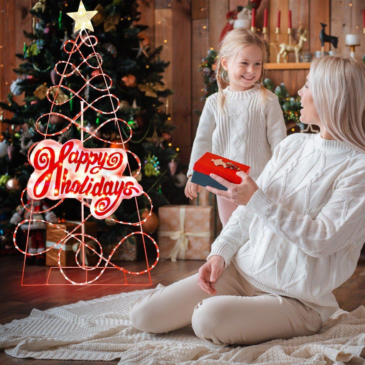 Una mujer y una niña intercambian regalos cerca de un árbol de Navidad. Un letrero de 'Felices Fiestas' está iluminado.