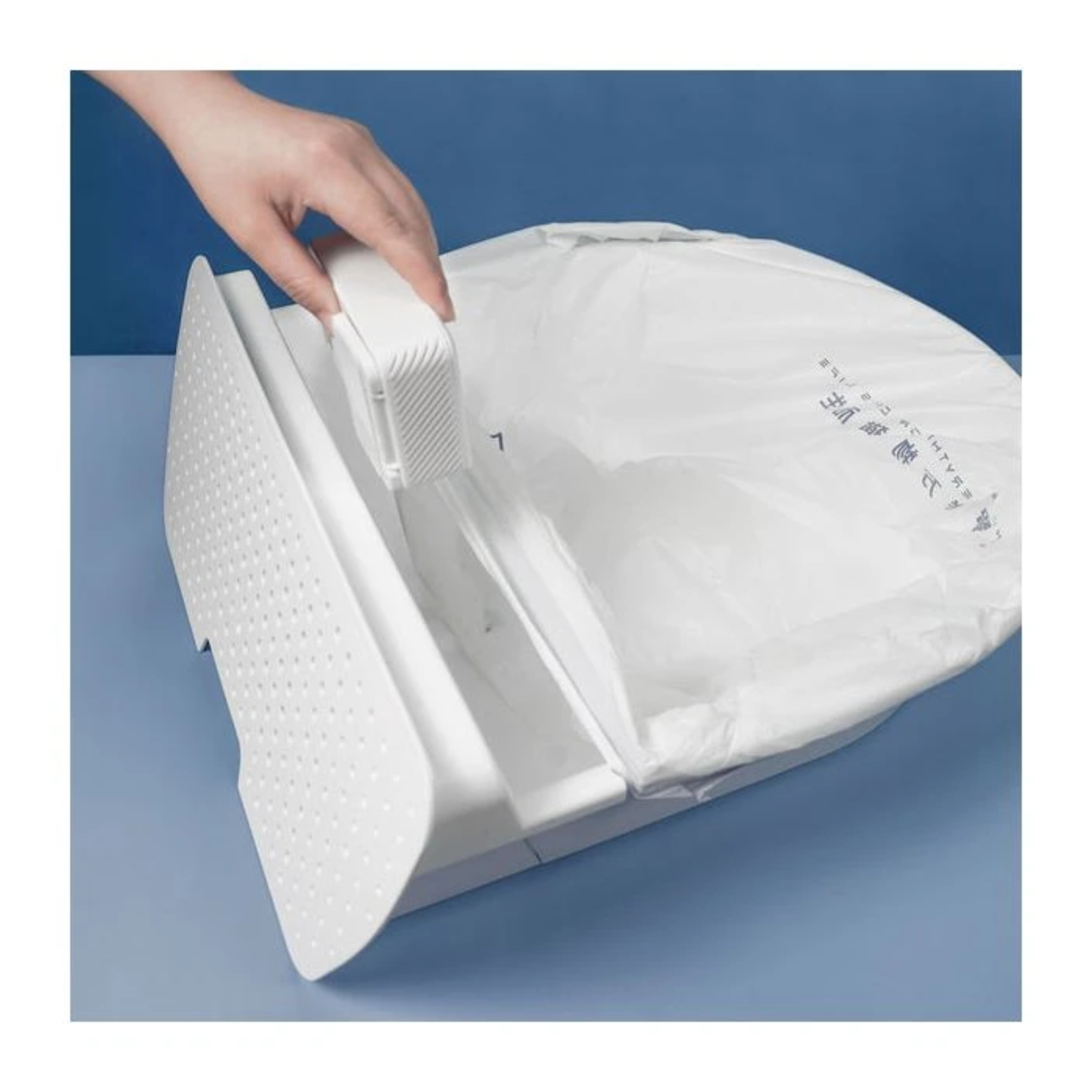 Hand öffnet eine weiße Plastiktüte in einem weißen Behälter. Der Hintergrund ist blau.