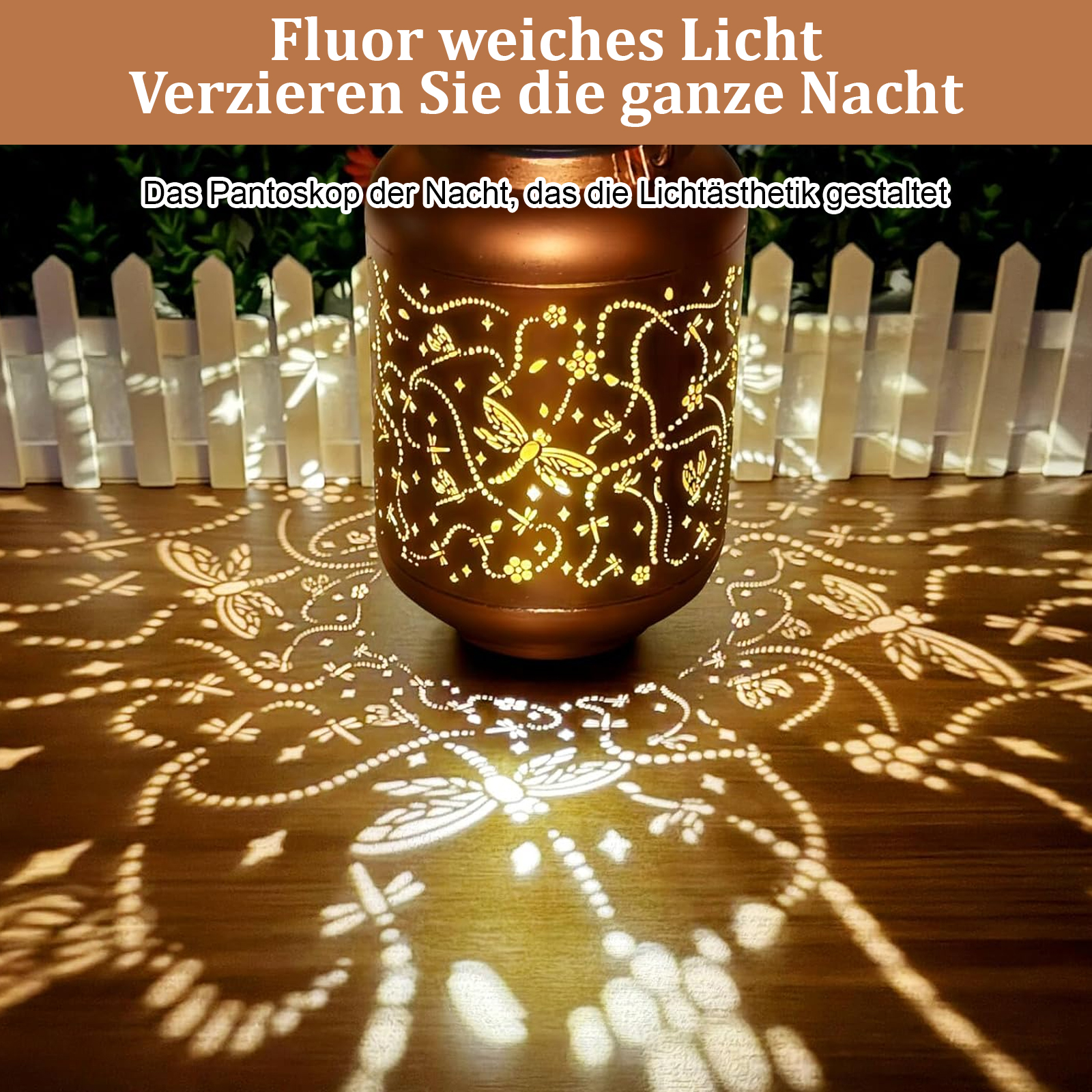 Eine dekorative Laterne, die ein Libellenmuster auf eine Holzoberfläche wirft, mit weißem Zaun im Hintergrund.