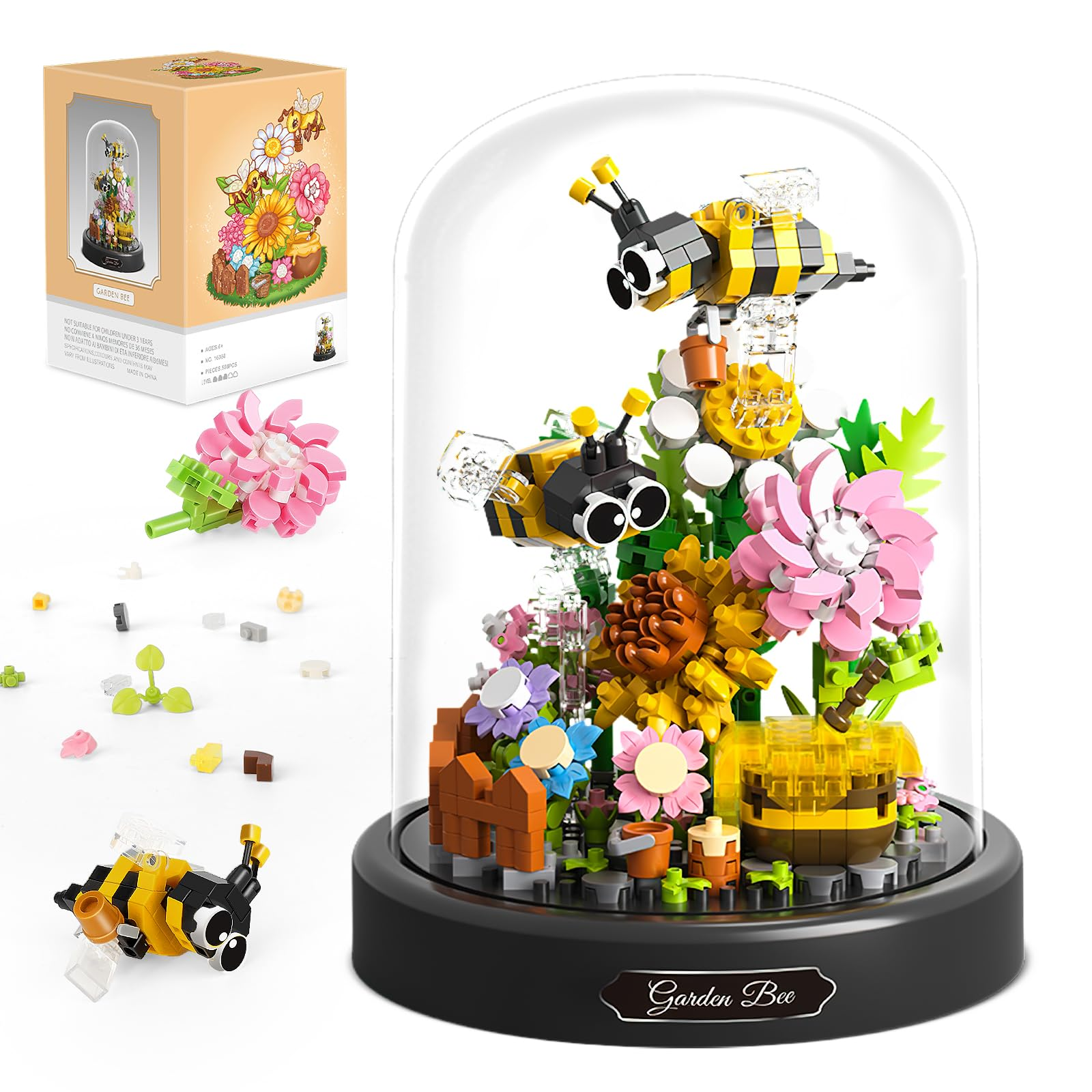 Ein Bienengartenmodell in einer Glaskuppel. Es zeigt Bienen, Blumen, einen Zaun und eine Schachtel mit dem Bild des Modells.