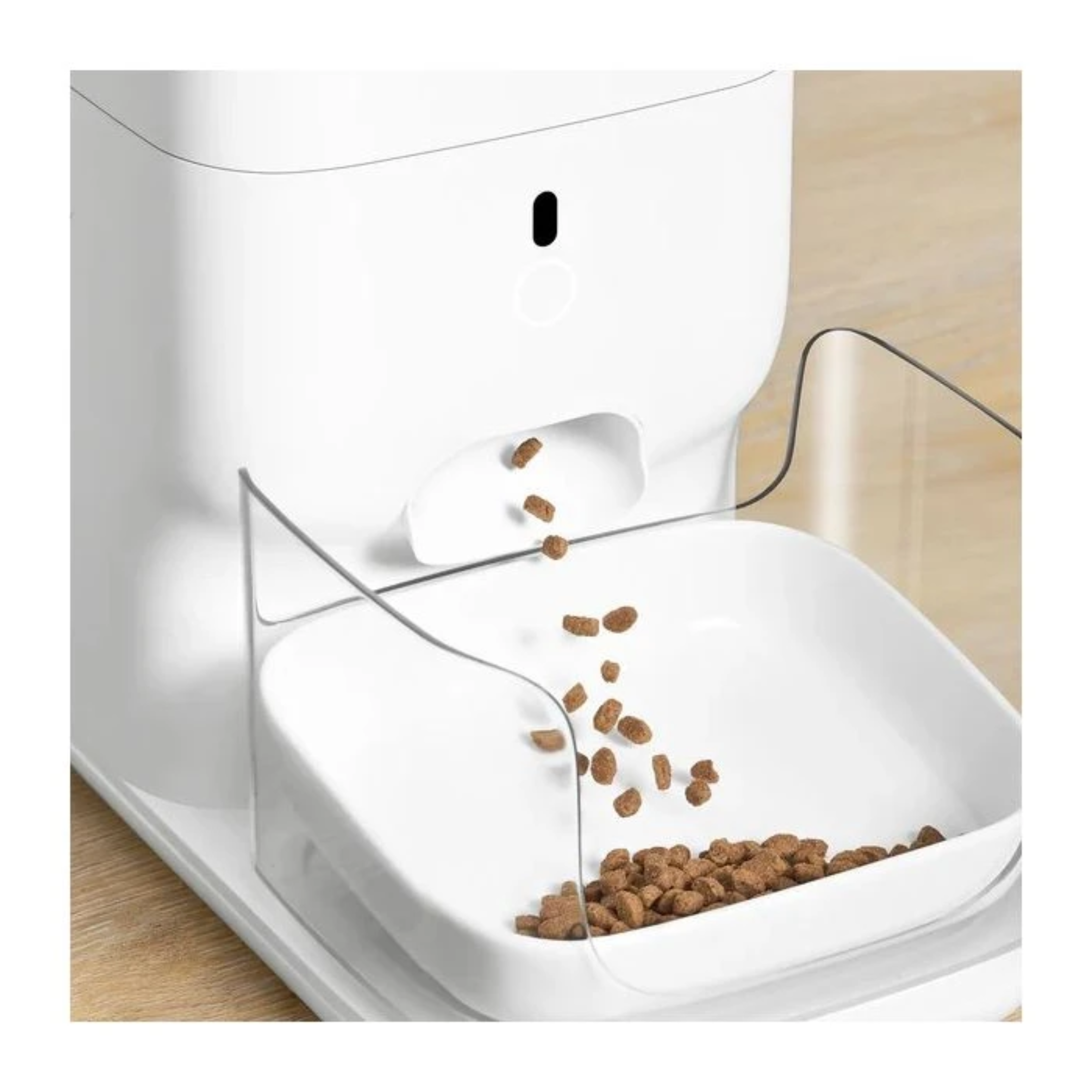 A white pet food dispenser. Brown kibble falls into a white bowl. A clear plastic guard is present.