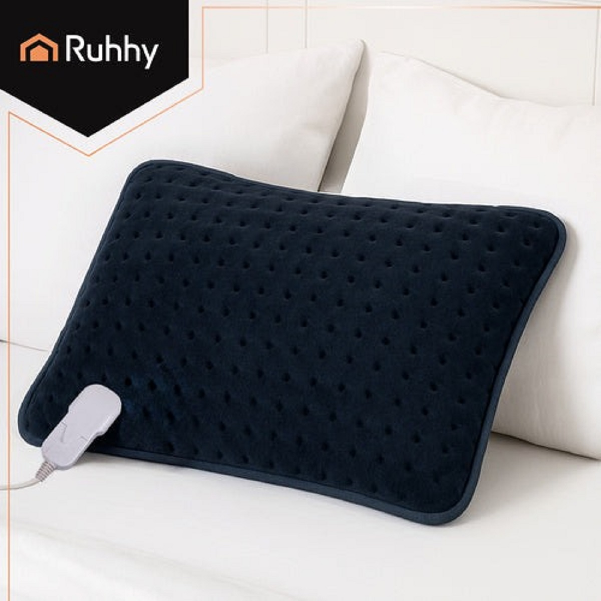 Una almohadilla térmica azul marino con un panel de control está sobre una cama blanca con almohadas blancas en el fondo. El logo de Ruhhy es visible.