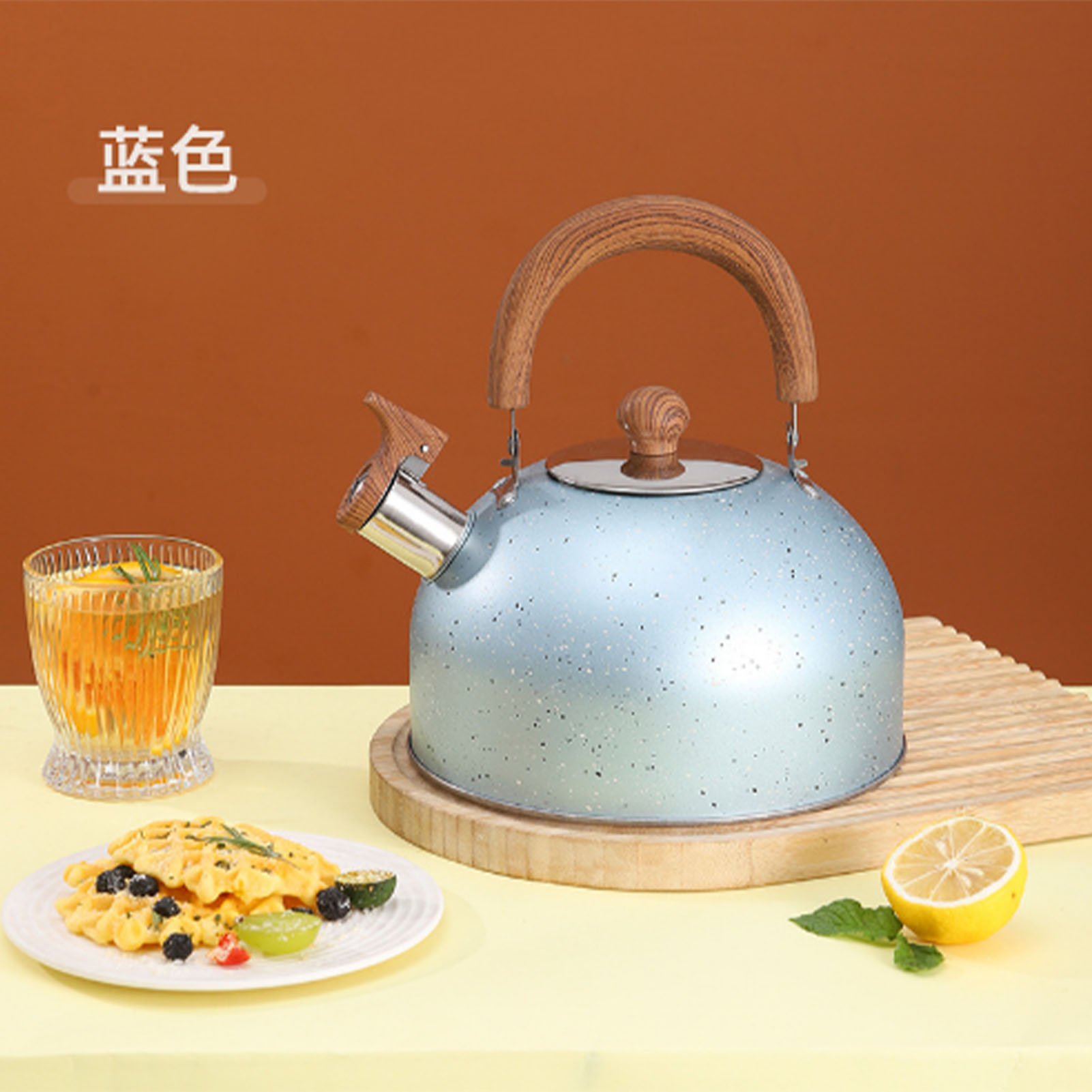 Blauer Wasserkocher mit Holzgriff, Waffeln, Zitrone, Getränk und Früchte auf gelbem Tisch, brauner Hintergrund.