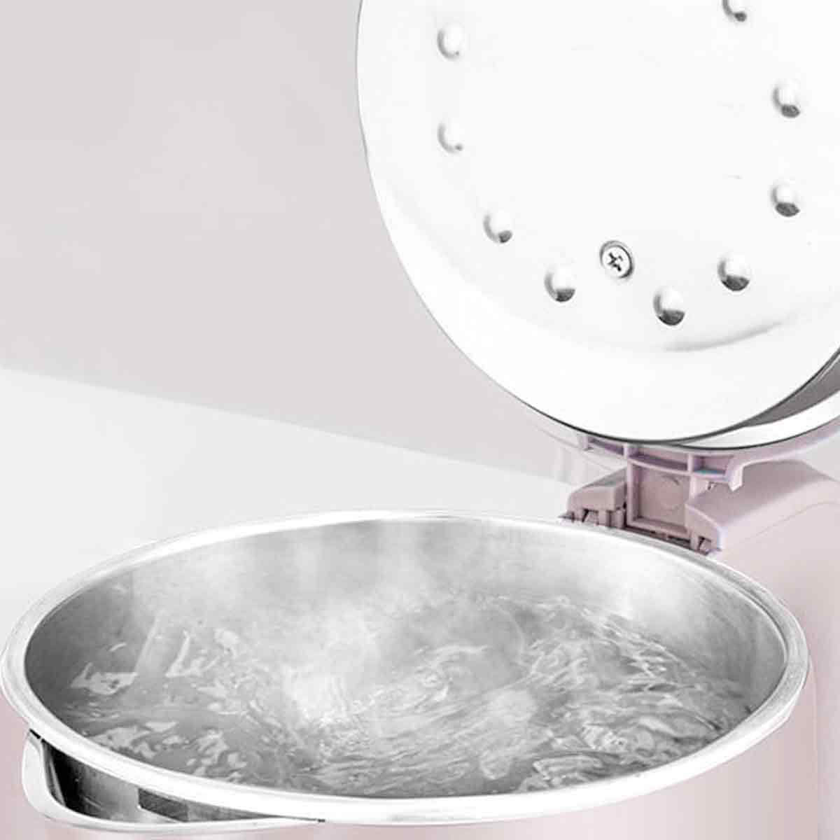Nahaufnahme eines Topfes mit kochendem Wasser, Dampf steigt auf. Der Deckel ist offen, der Topf aus Stahl. Weißer Hintergrund.