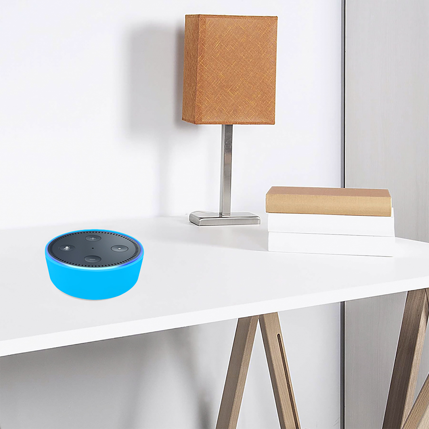 Un altoparlante intelligente blu su una scrivania bianca. Una lampada e dei libri sullo sfondo.