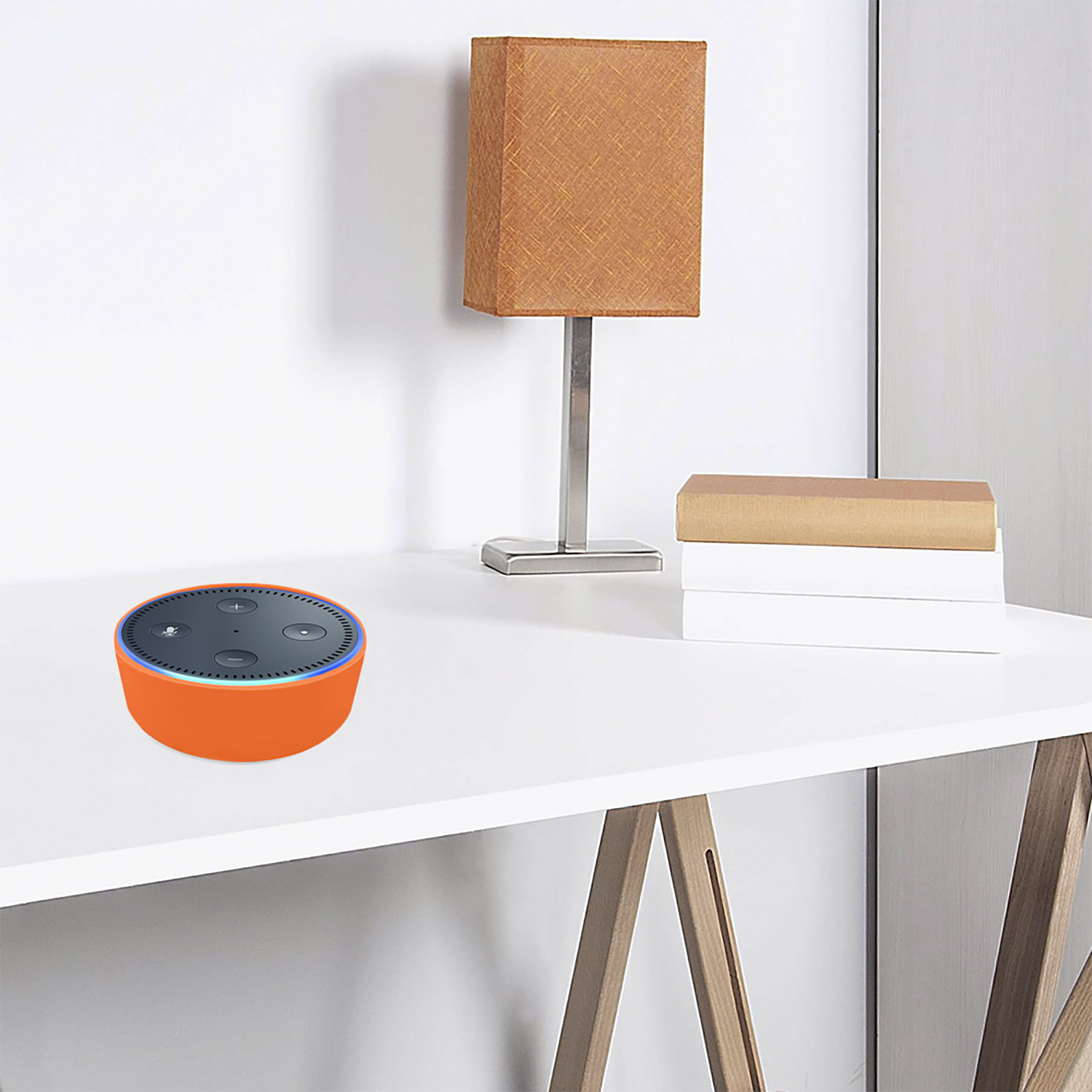 Un altoparlante intelligente arancione su una scrivania bianca con una lampada e libri. La lampada ha un paralume arancione. Lo sfondo è bianco.