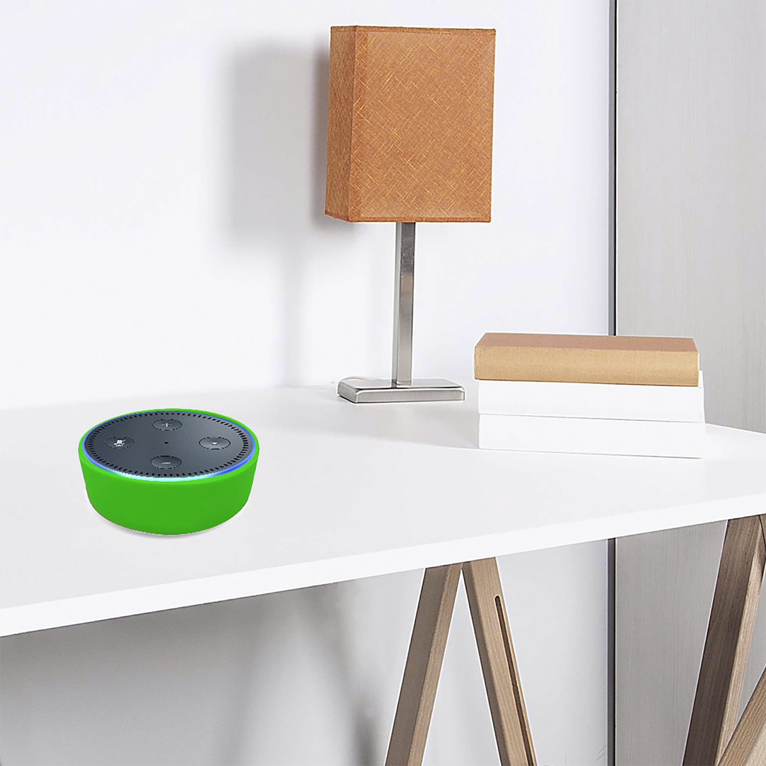 Ein grüner Smart-Lautsprecher steht auf einem weißen Schreibtisch. Eine Lampe und Bücher stehen dahinter. Der Hintergrund ist eine weiße Wand.