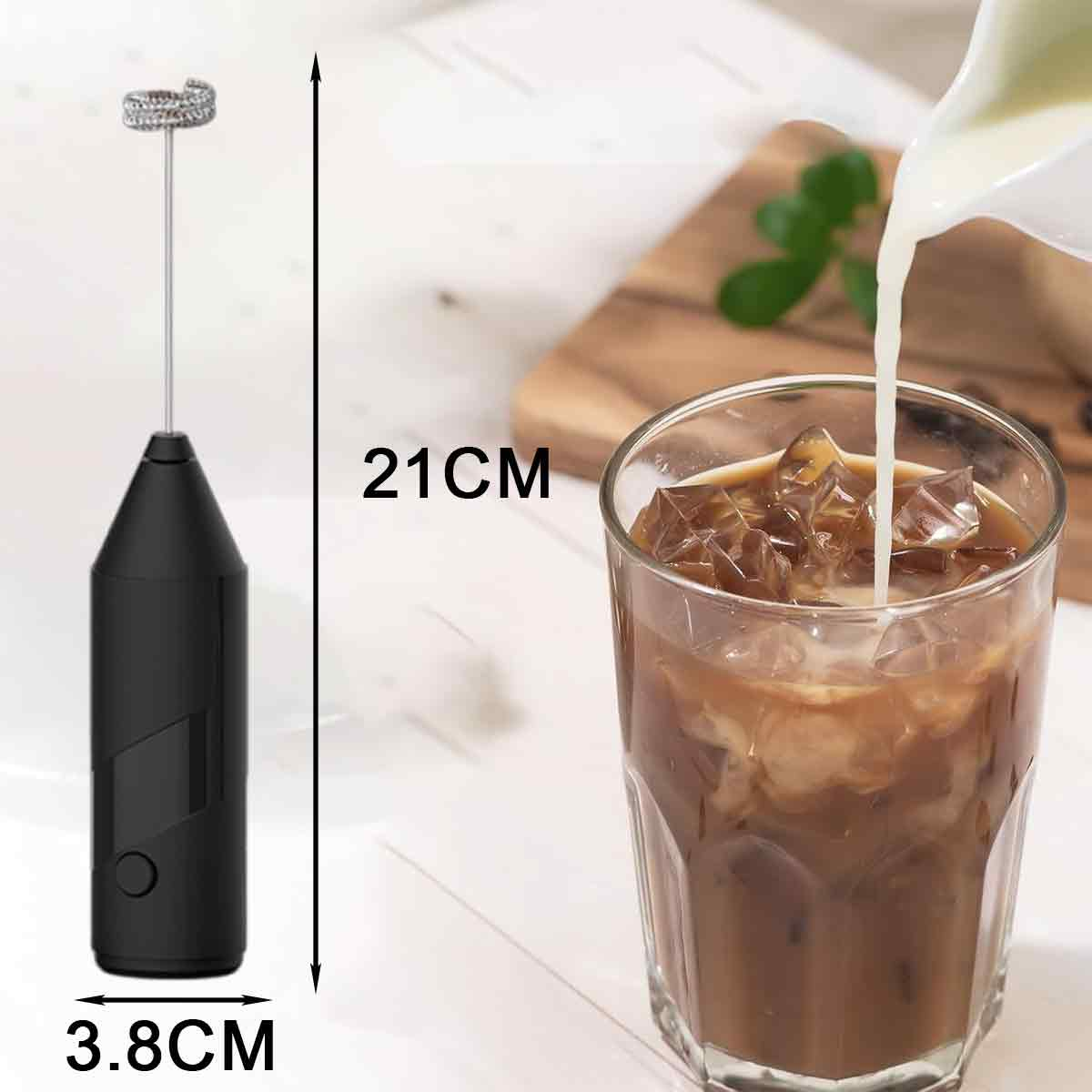 Ein Milchaufschäumer und ein Glas Eiskaffee in Zubereitung. Milch wird in das Glas gegossen. Holzbrett im Hintergrund.